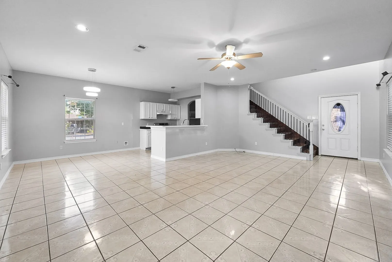 Open-concept living area featuring tile flooring, white cabinetry, and a ceiling fan