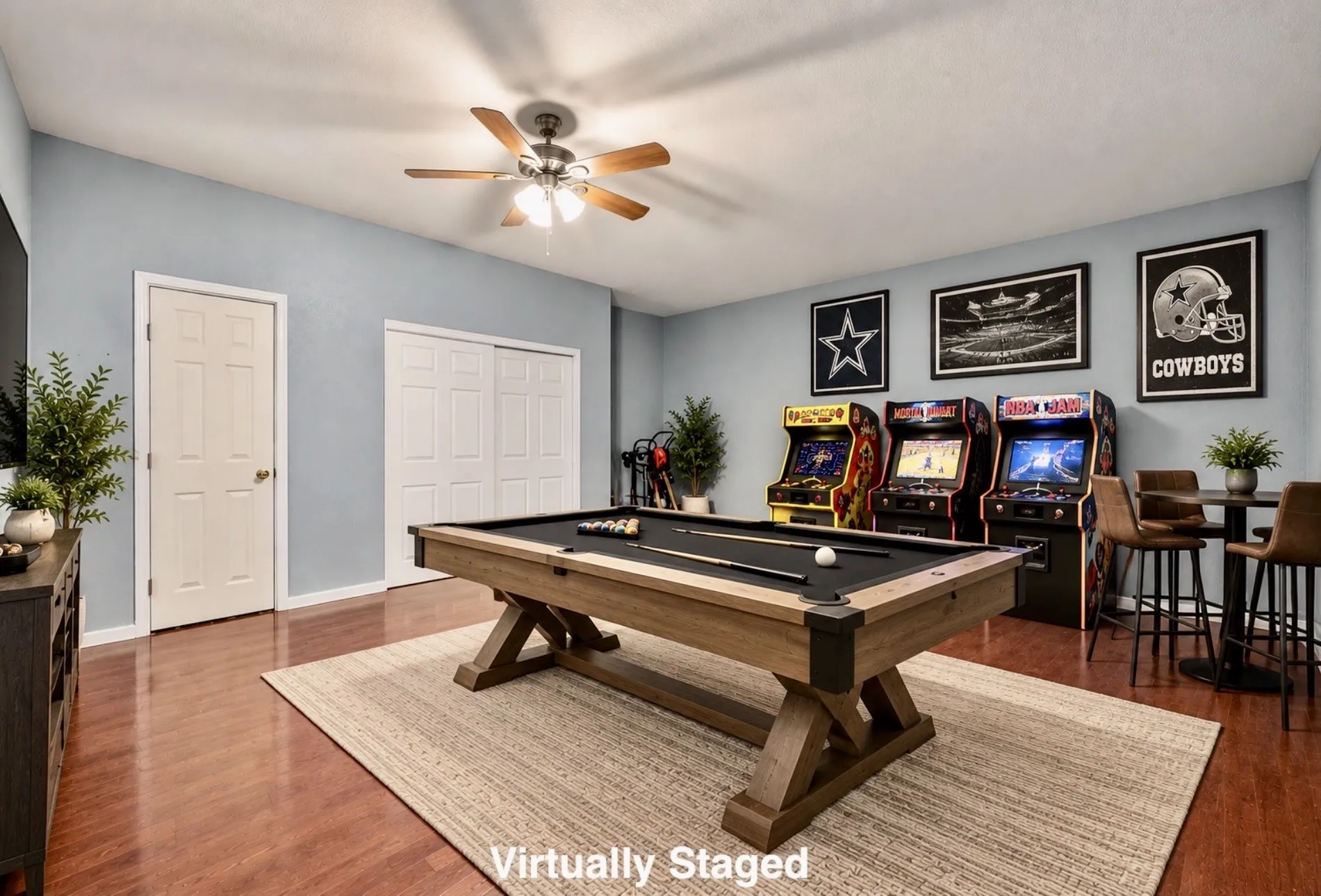 Wood-finish flooring, ceiling fan with light fixture, light blue wall paint, white trim, and white paneled doors