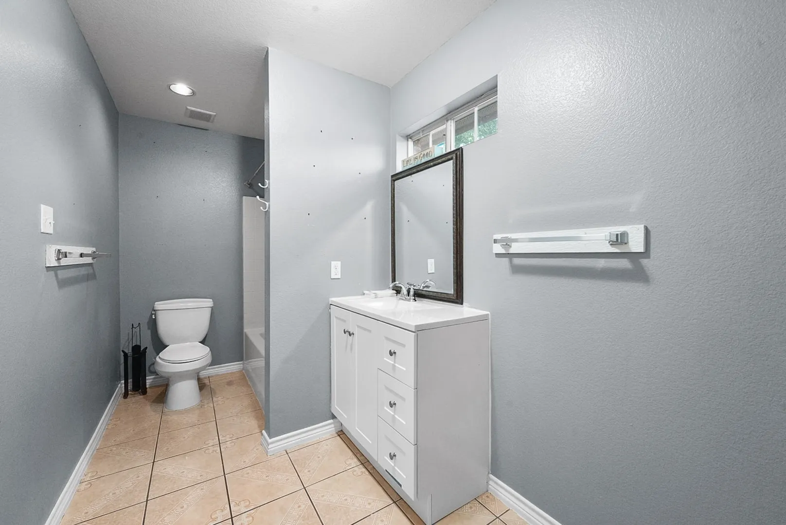 White vanity with silver-finish hardware, rectangular sink, and framed mirror
