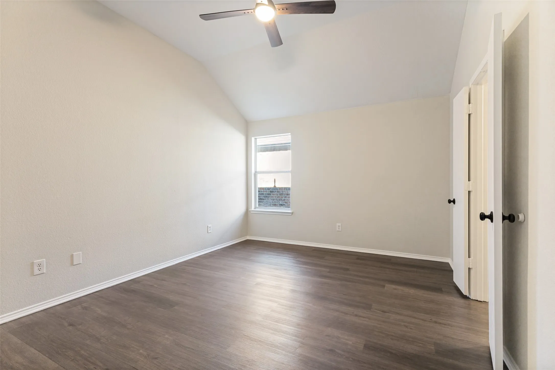 Vaulted ceiling with a ceiling fan, wood-finish flooring, and a multi-pane window