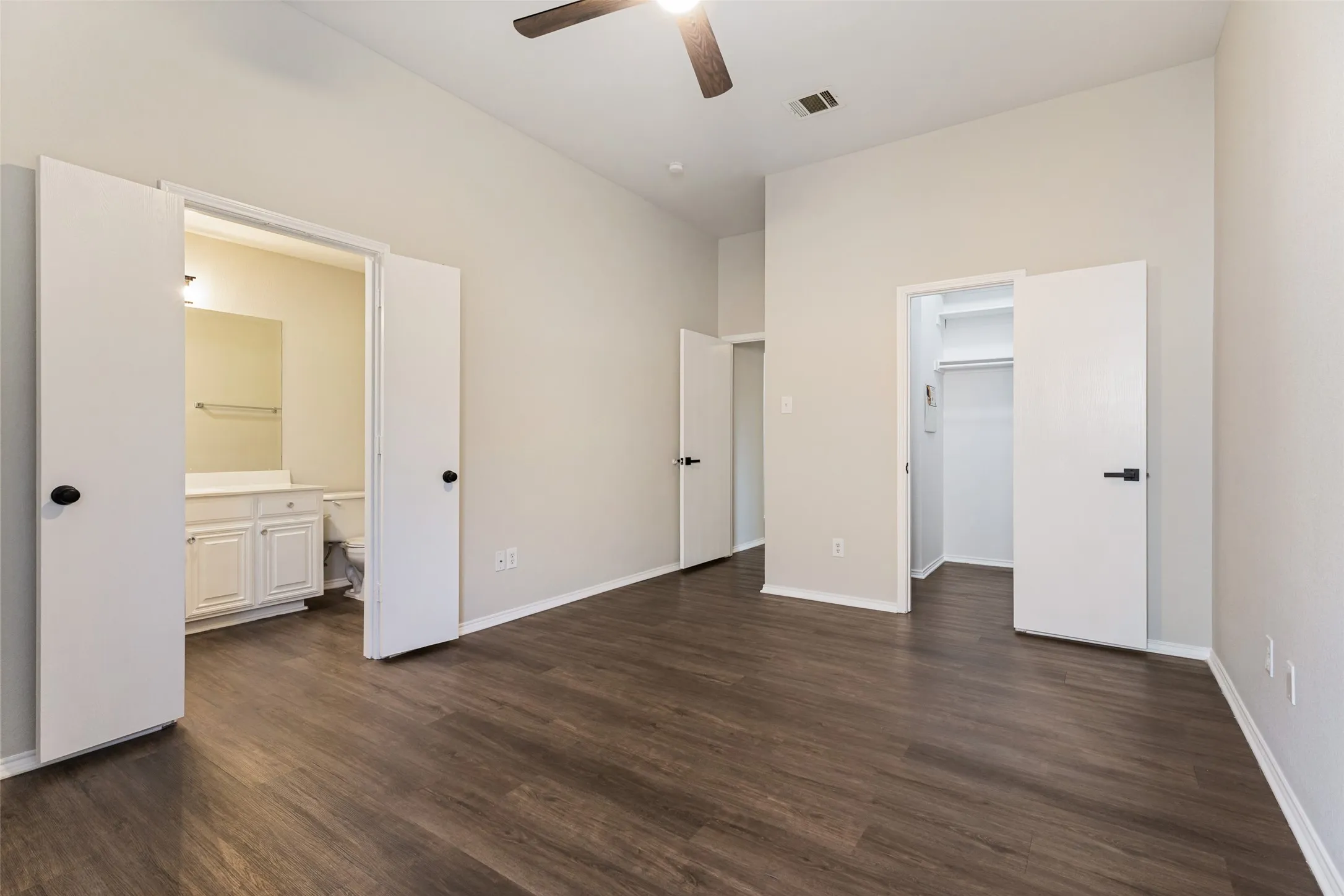 Vaulted ceiling with a ceiling fan, wood-finish flooring, and white interior doors with black hardware