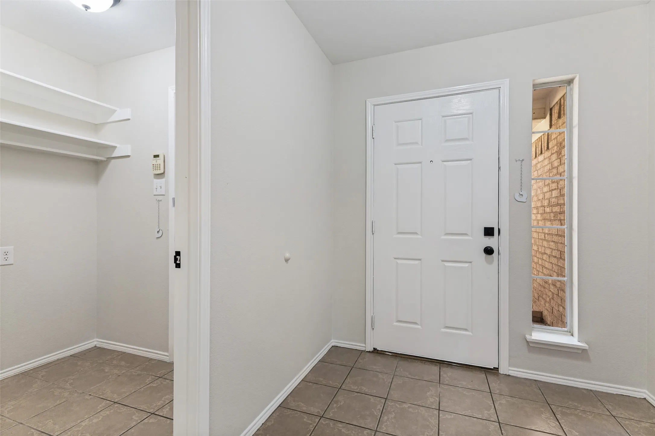 White paneled entry door, sidelight window, and tile flooring