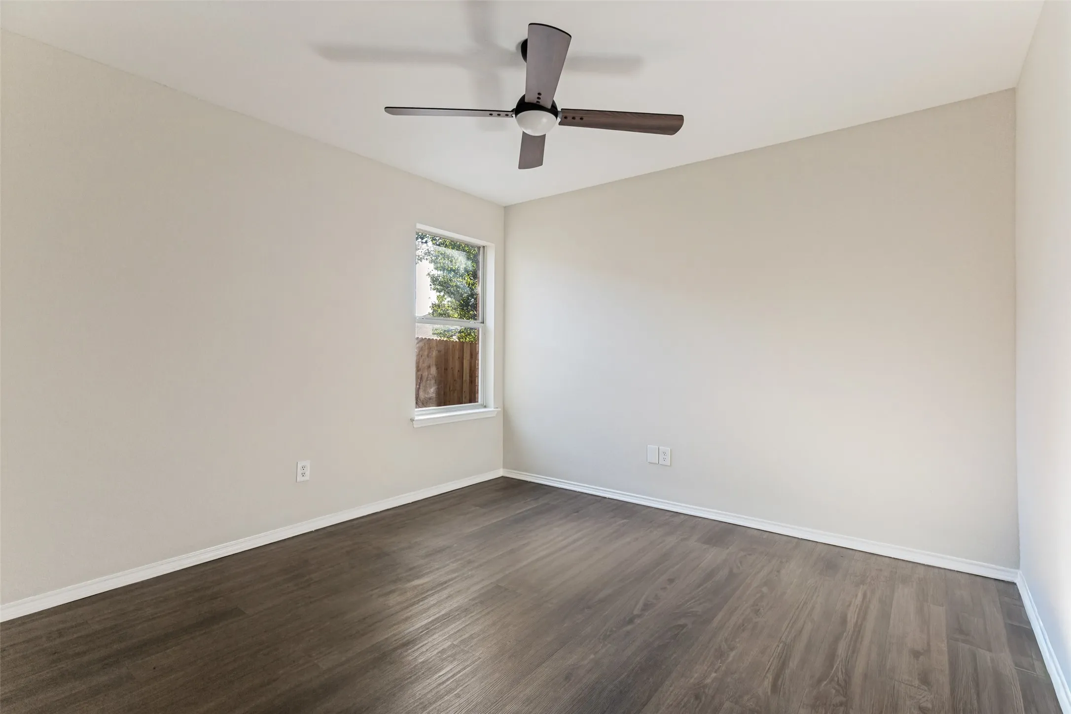Wood-finish flooring, neutral wall paint, and a ceiling fan with light fixture