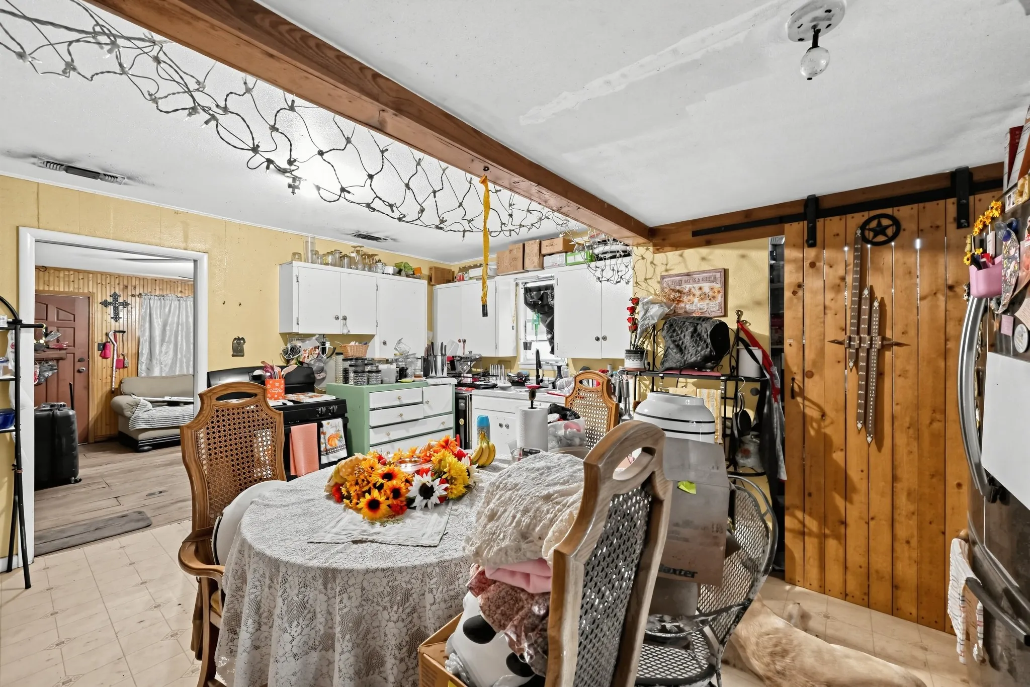 Kitchen featuring white cabinetry, wood-finish flooring, and a wood beam accent