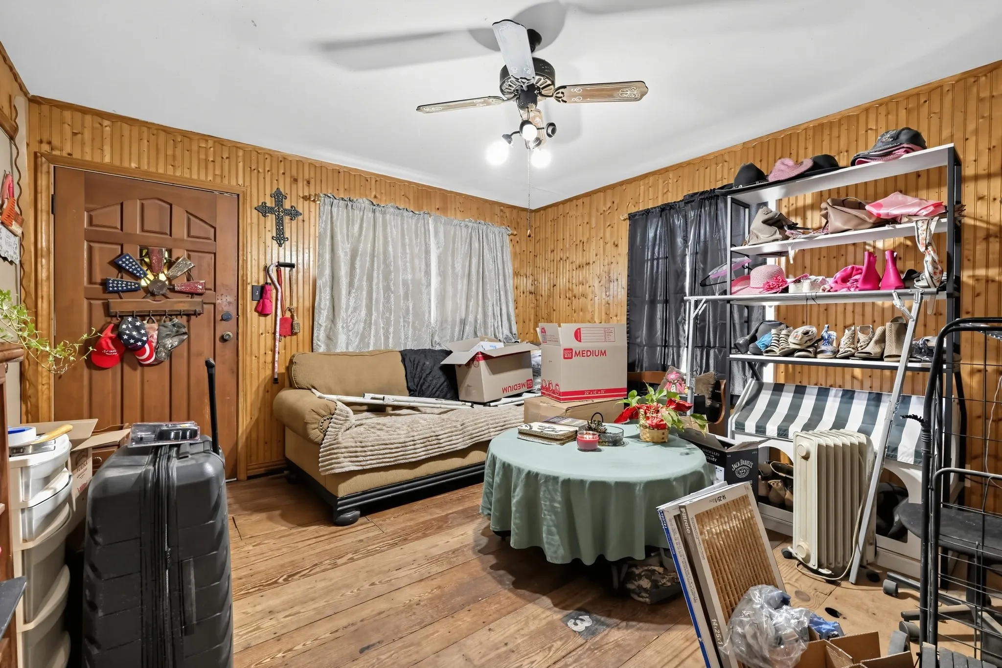 Wood-paneled walls with wood-finish flooring, featuring a ceiling fan with integrated lighting and a built-in shelving unit