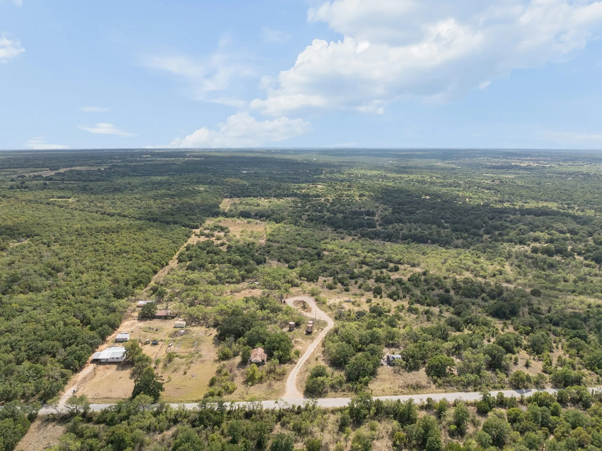 Expansive property featuring dense tree coverage, a private road, and multiple structures