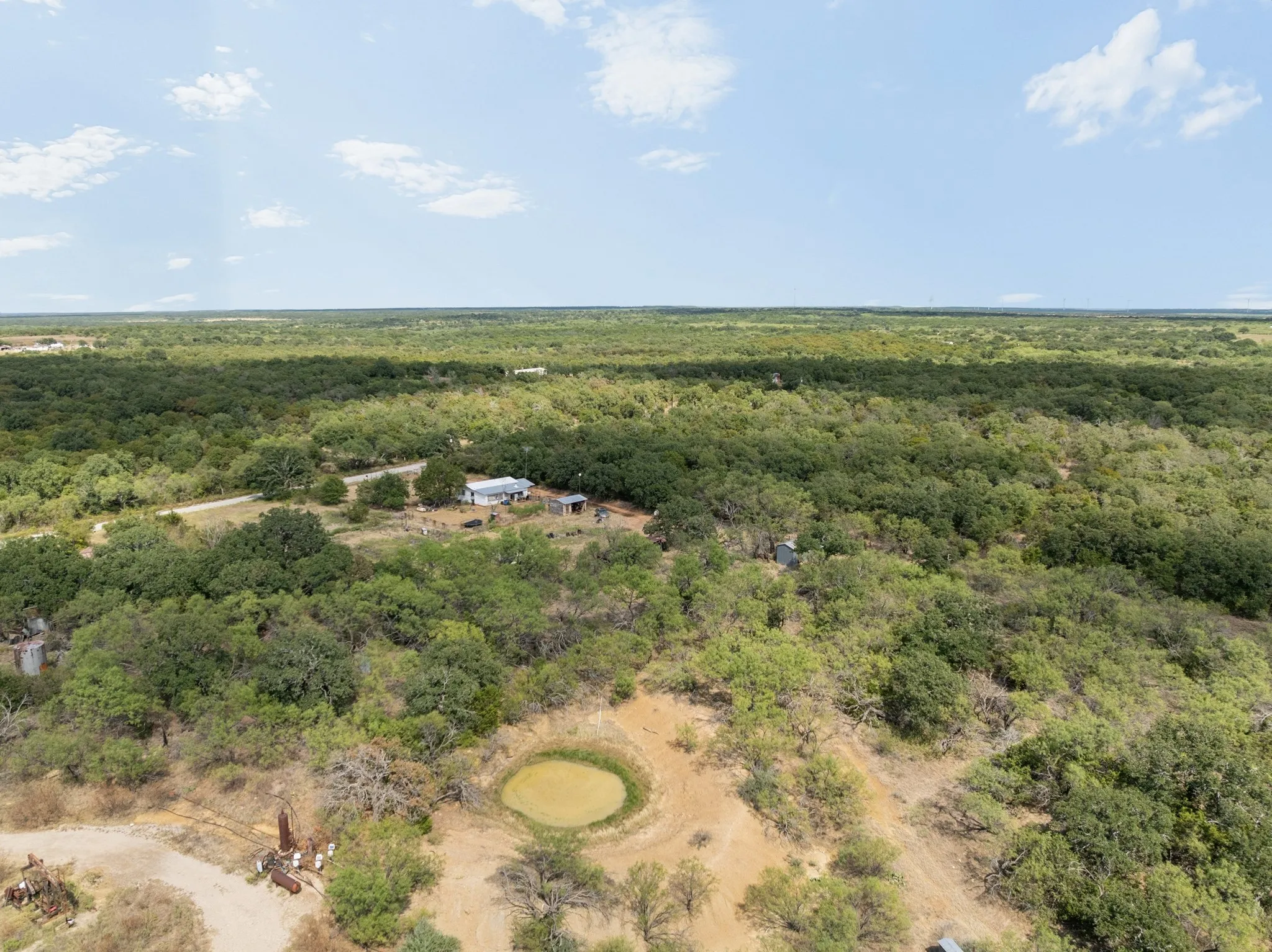 Expansive wooded acreage featuring a visible structure, a water feature, and extensive tree coverage