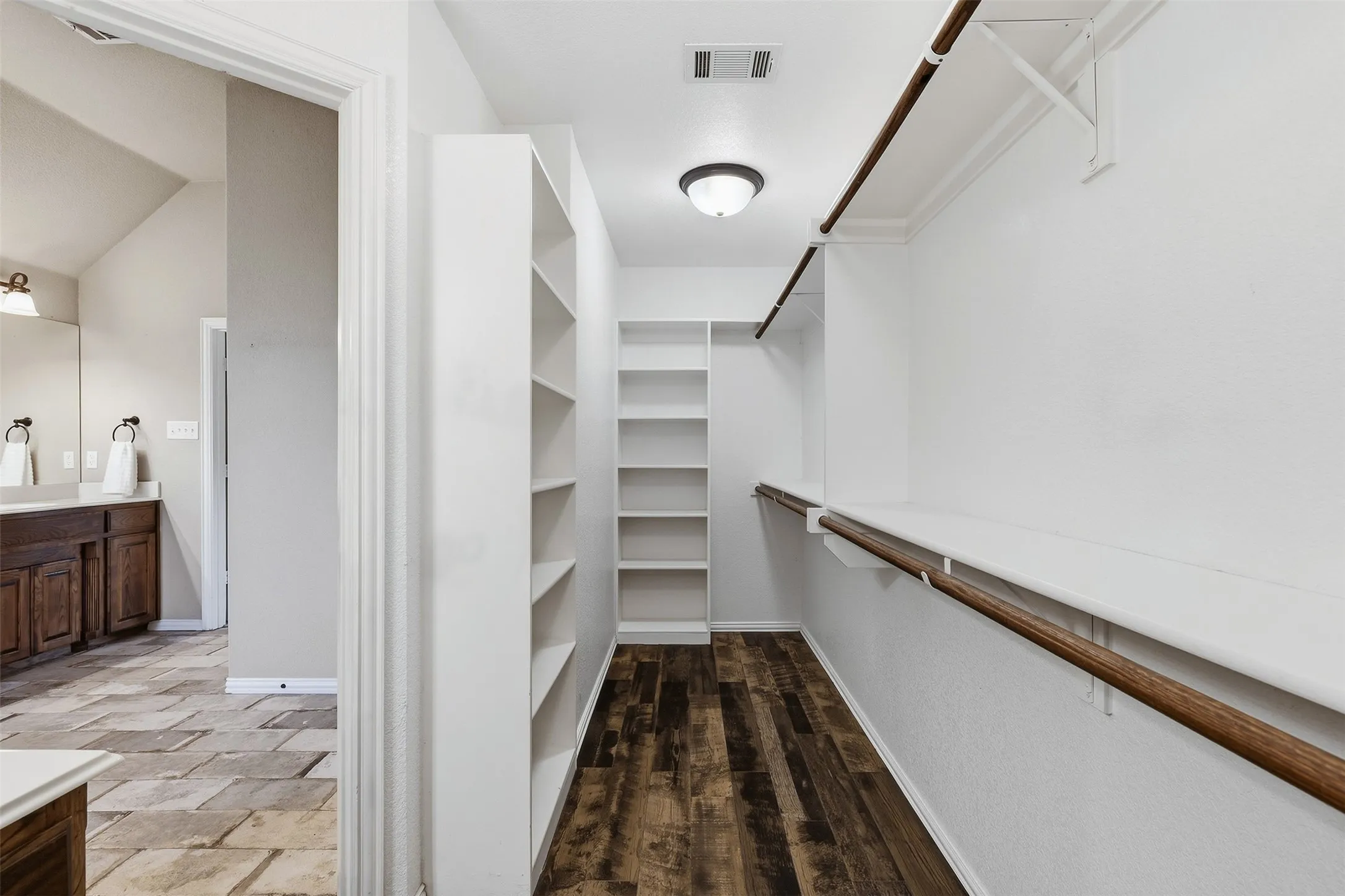 Walk-in closet with extensive built-in shelving, hanging rods, and wood-finish flooring