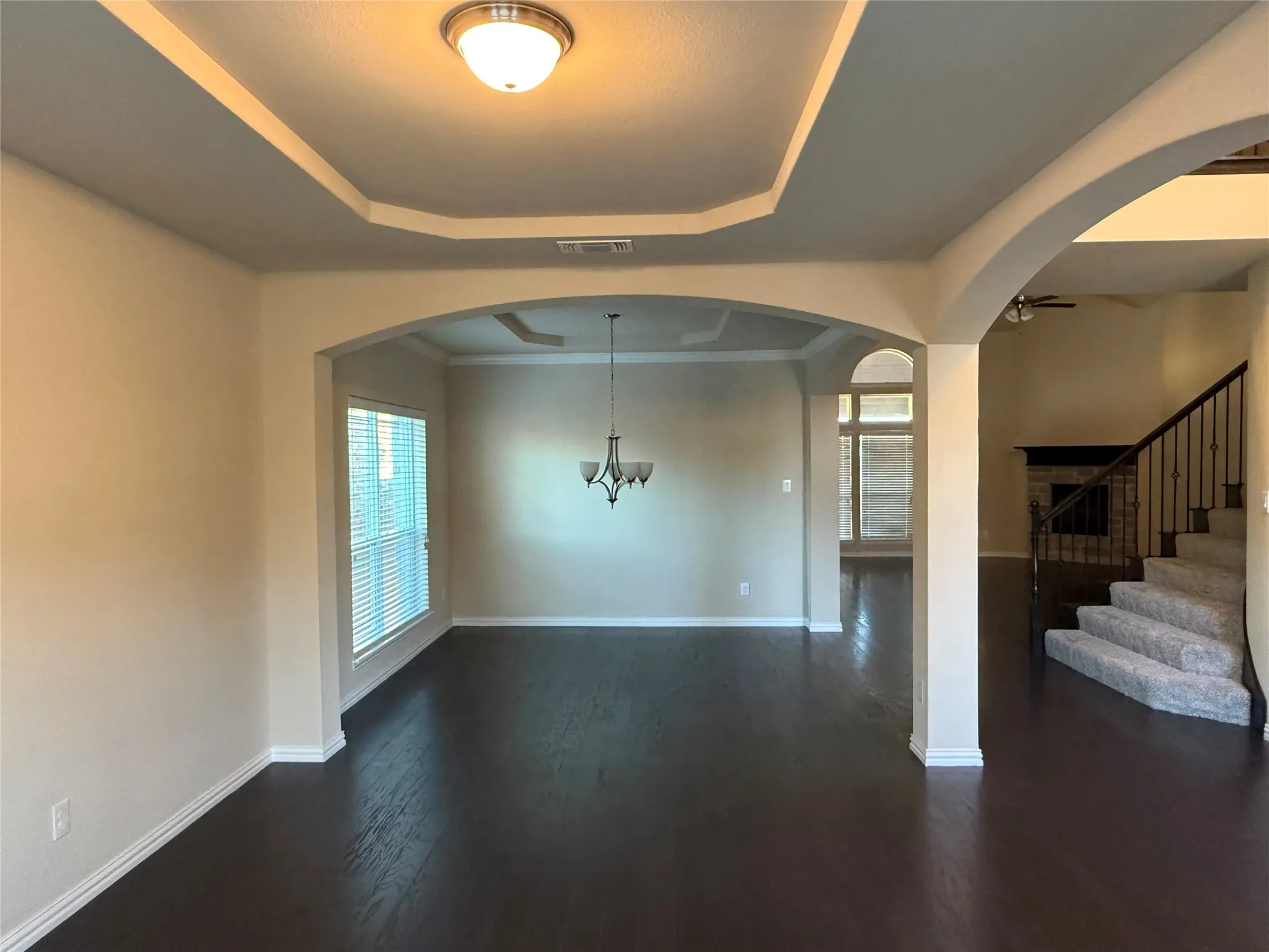 Tray ceiling with crown molding, dark wood-finish flooring, arched doorways, and a traditional​​‌​​​​‌​​‌‌​‌‌​​​‌‌​‌​‌​‌​​​‌​​ chandelier