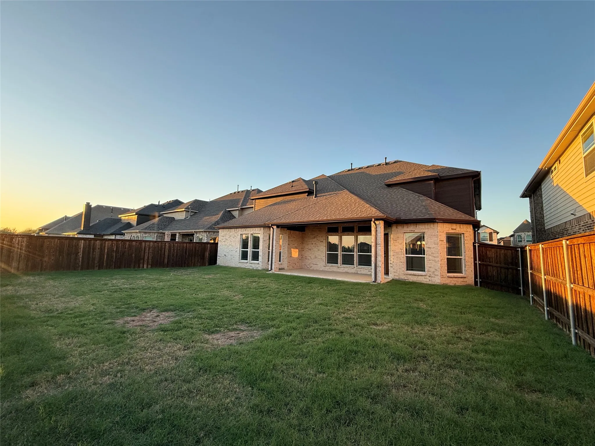 Expansive grassy yard with full privacy fencing and a covered patio
