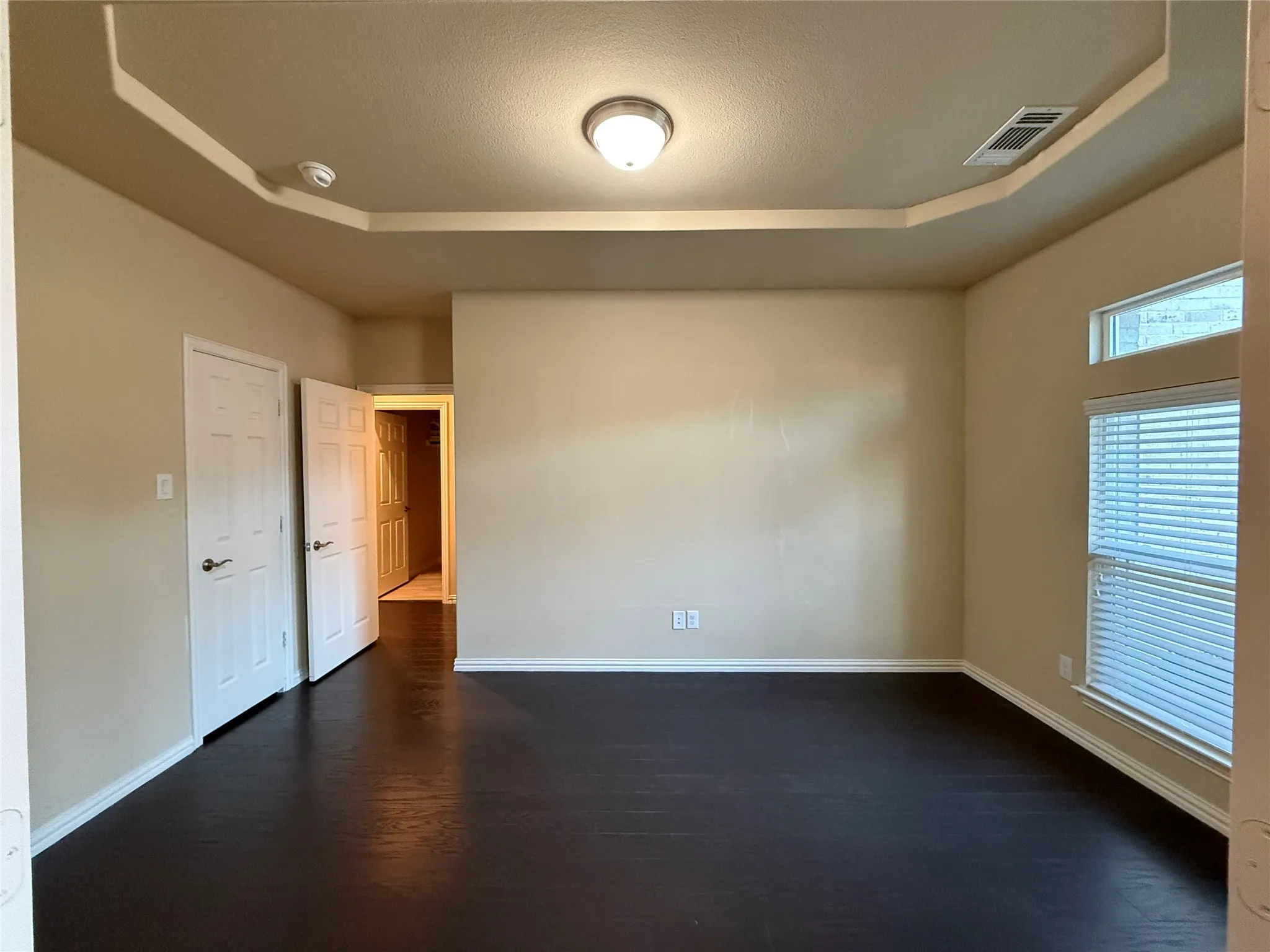 Tray ceiling with recessed lighting, dark wood-finish flooring, and white trim