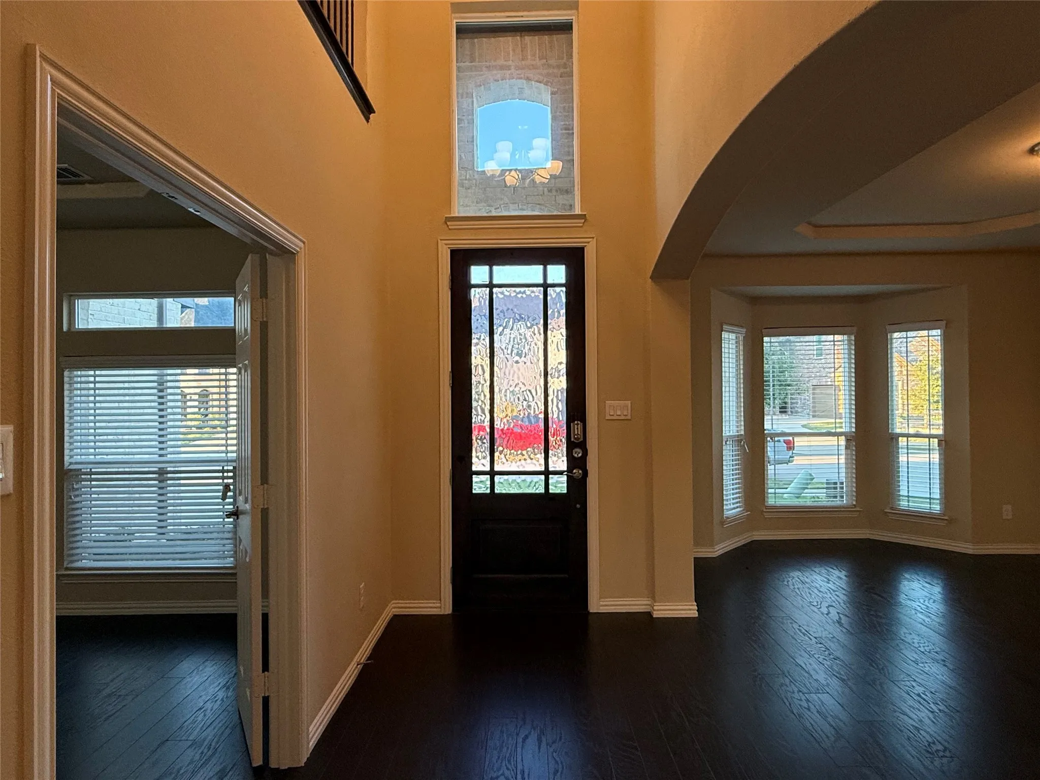 Two-story entry with dark wood-finish flooring, a decorative glass paneled front door, and a transom window