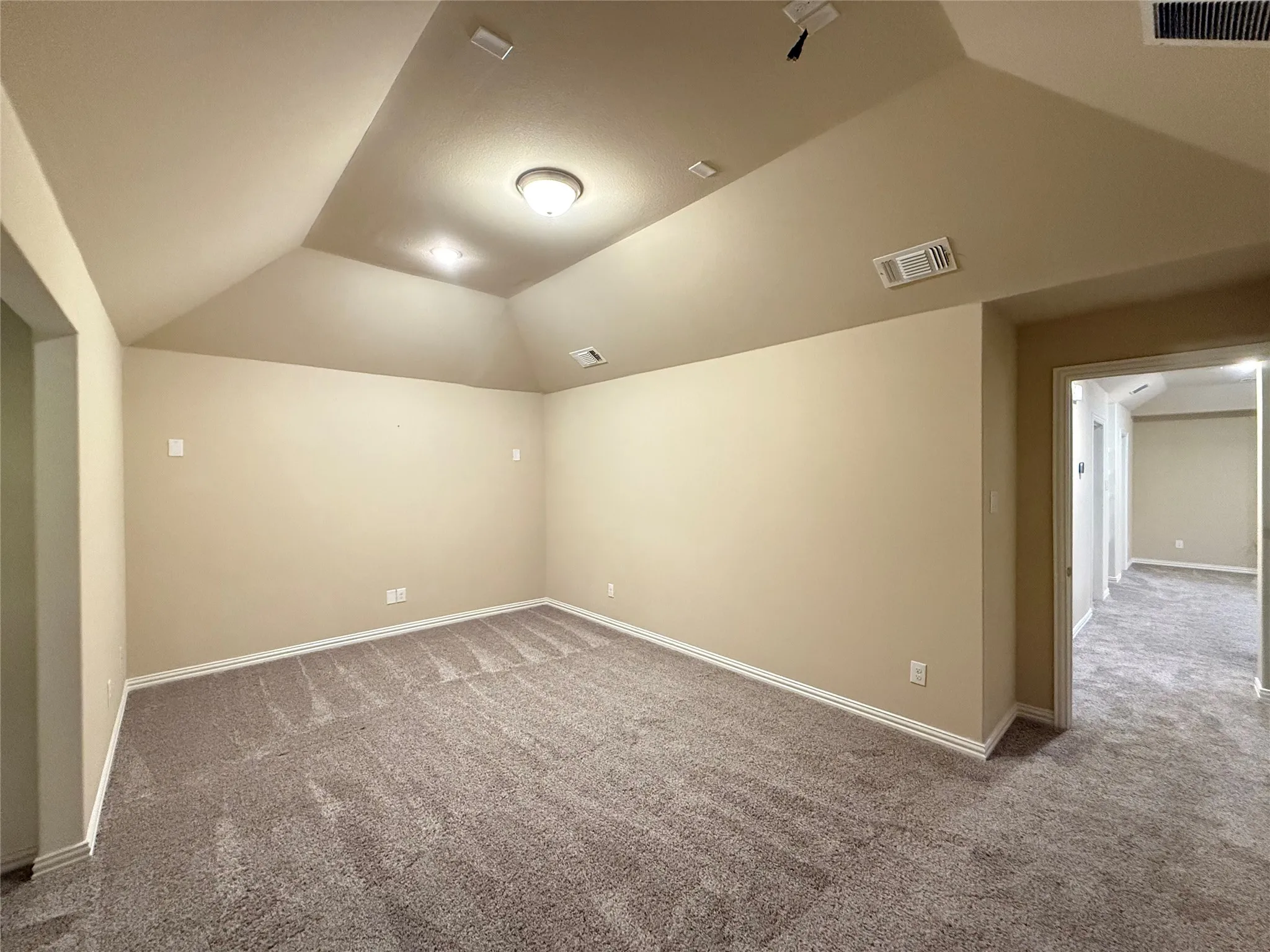 Vaulted ceiling with recessed lighting and a central flush-mount fixture, neutral carpet flooring, and painted walls