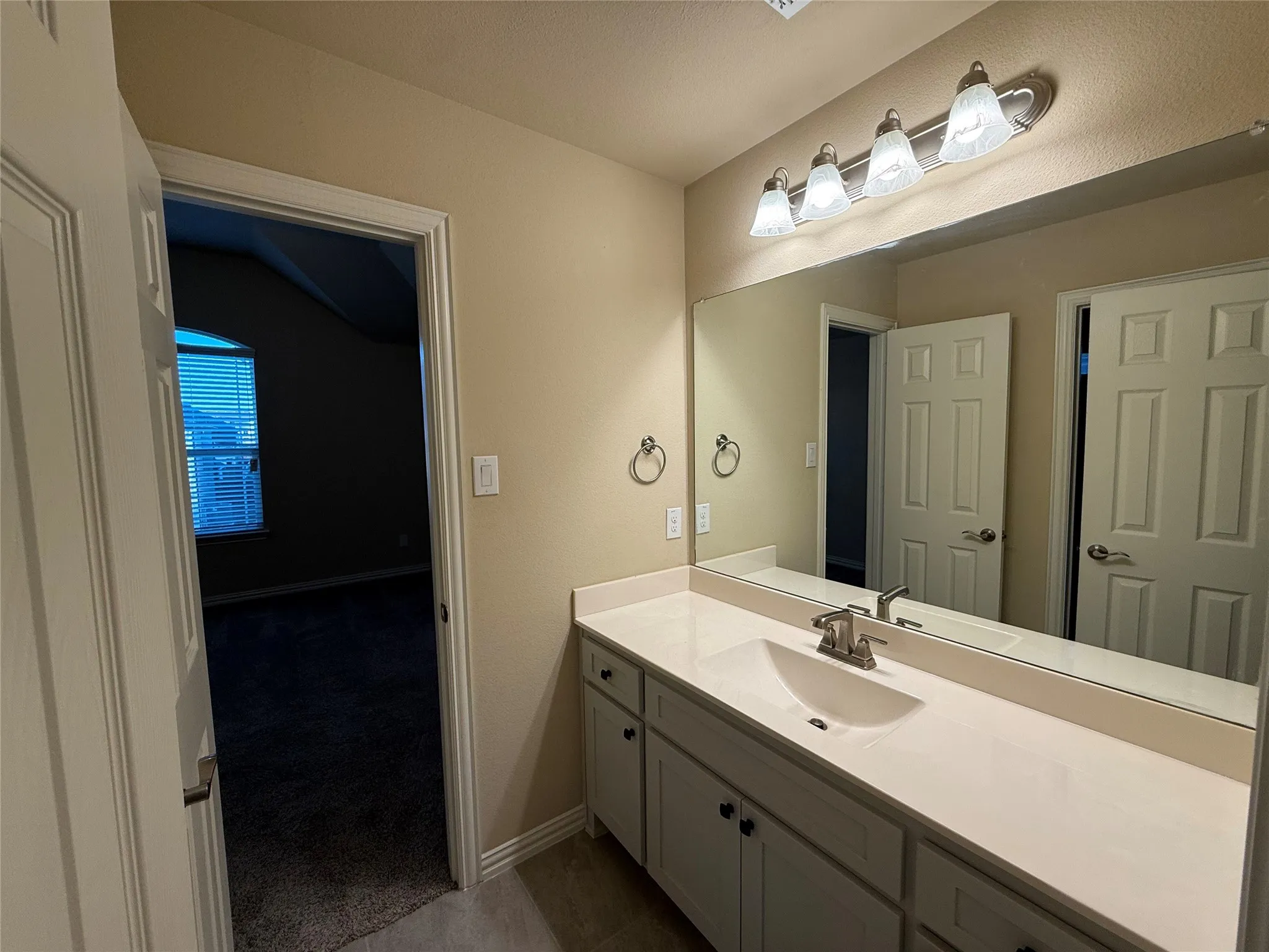 Vanity featuring an integrated sink, brushed nickel faucet, and white cabinetry with dark hardware