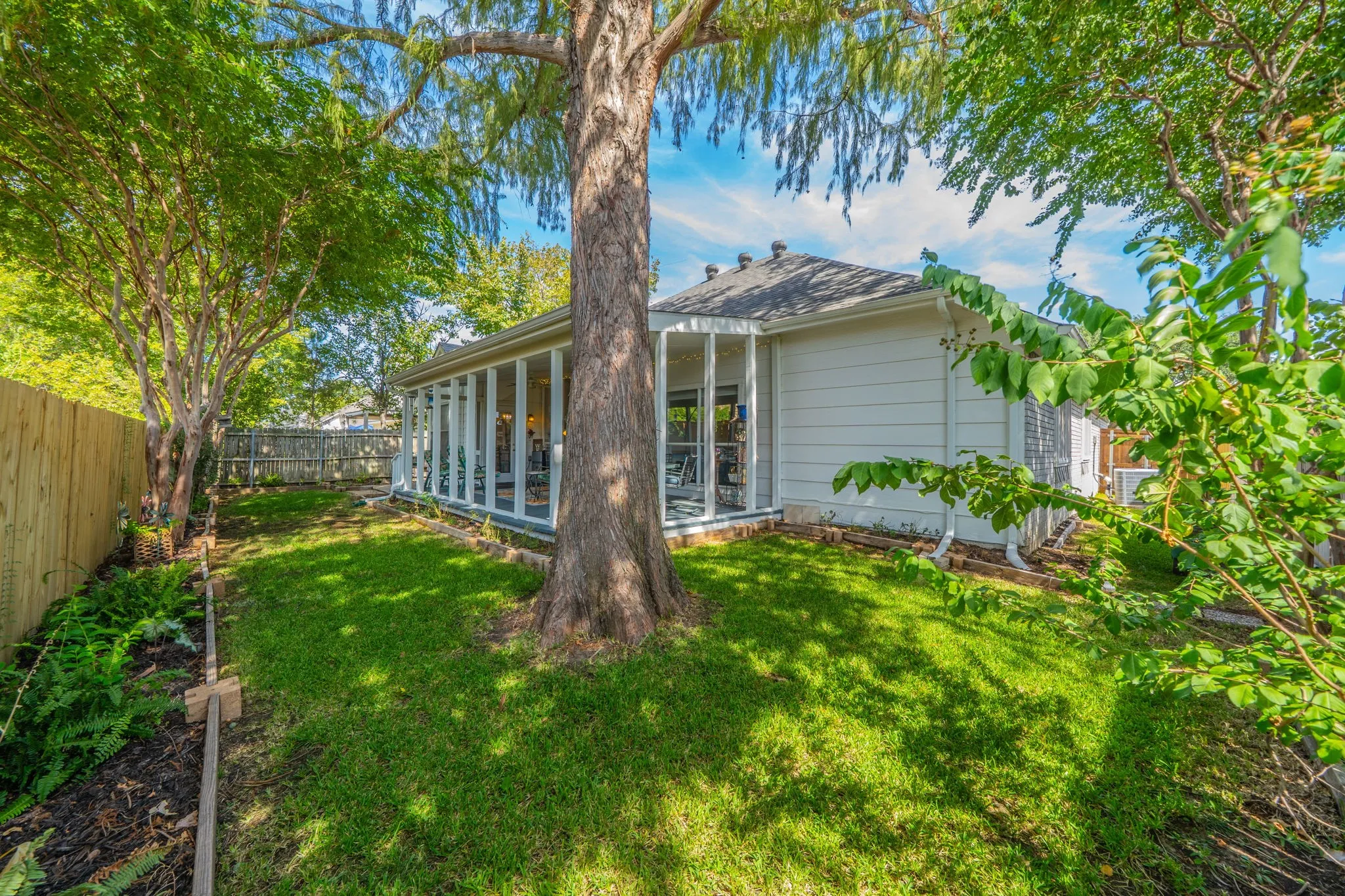 Expansive backyard with a manicured lawn, established trees, and perimeter fencing