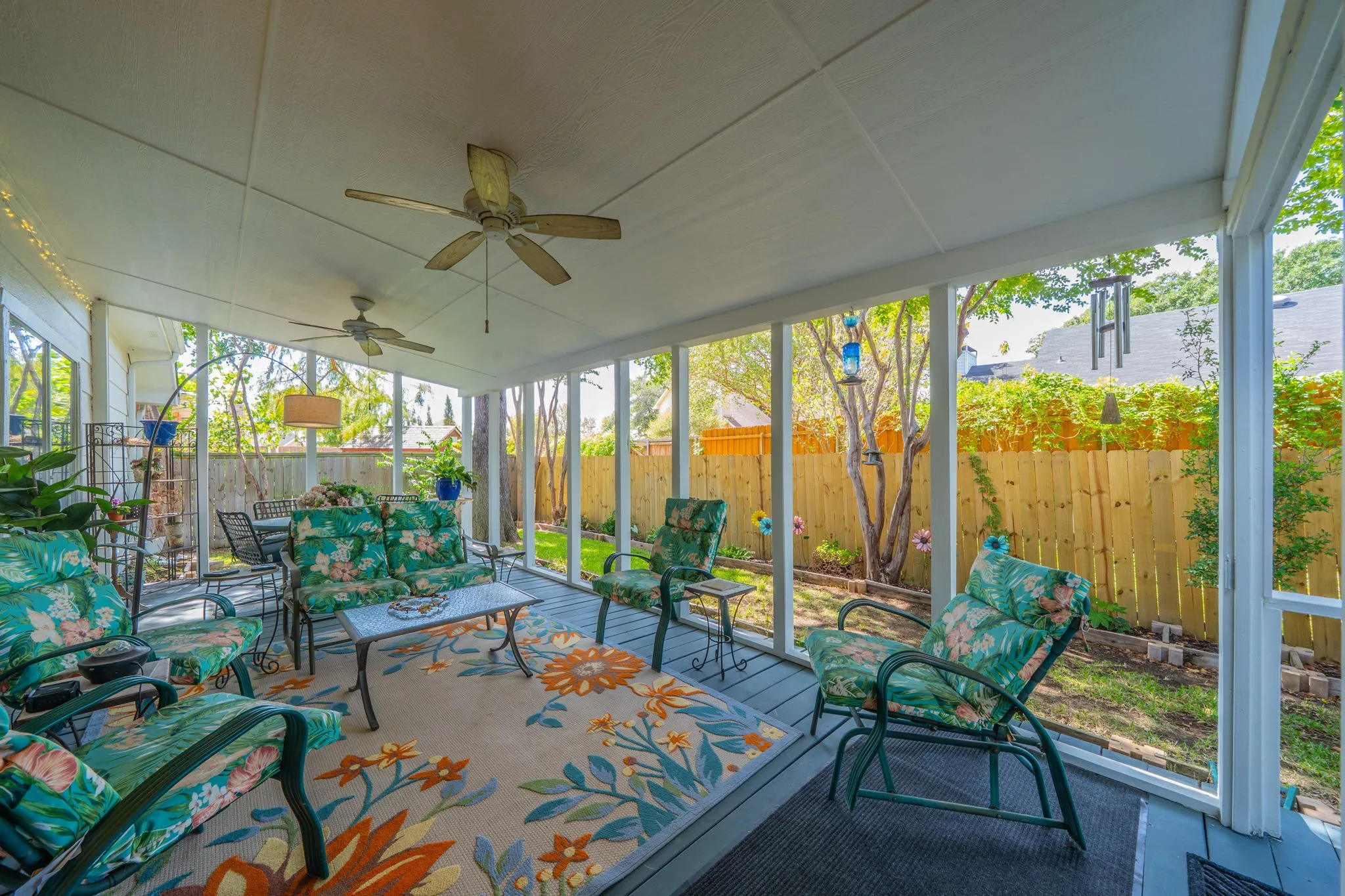 Covered porch with two ceiling fans, wood-finish flooring,  mature trees