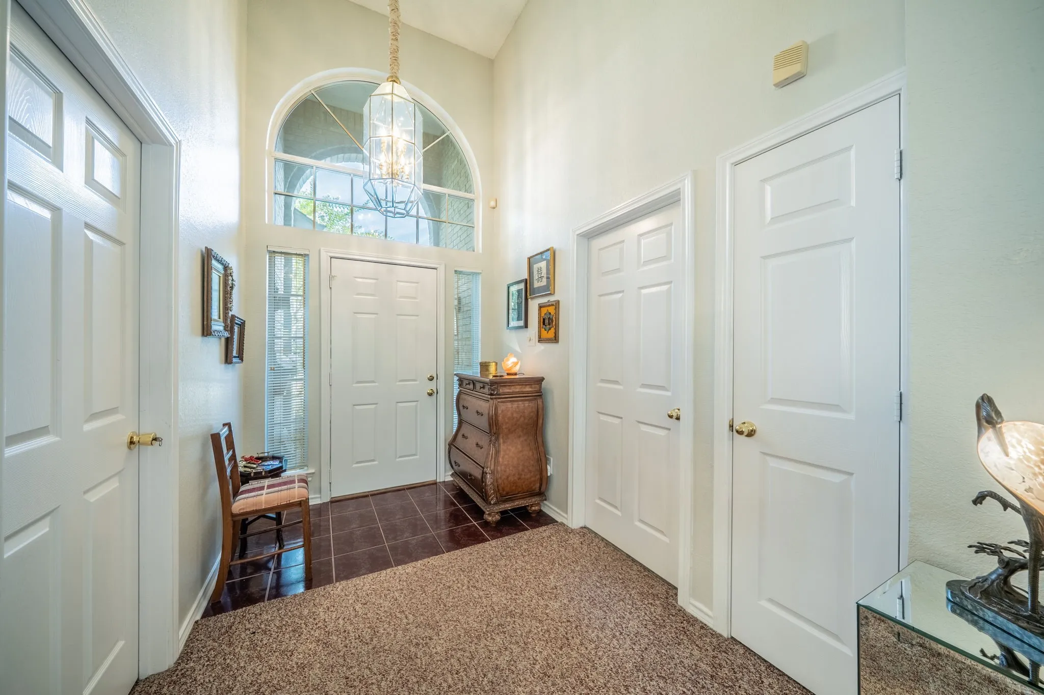 Grand entryway featuring a vaulted ceiling and an arched transom window above a panel front door with side windows