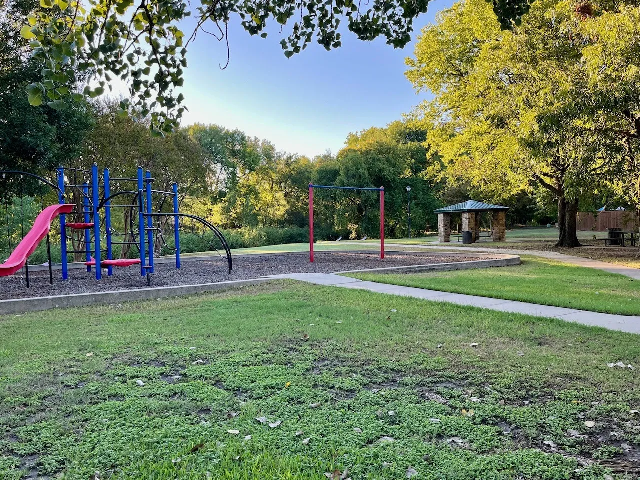 Playground with a slide and climbing structure, swing set, and a stone-clad gazebo