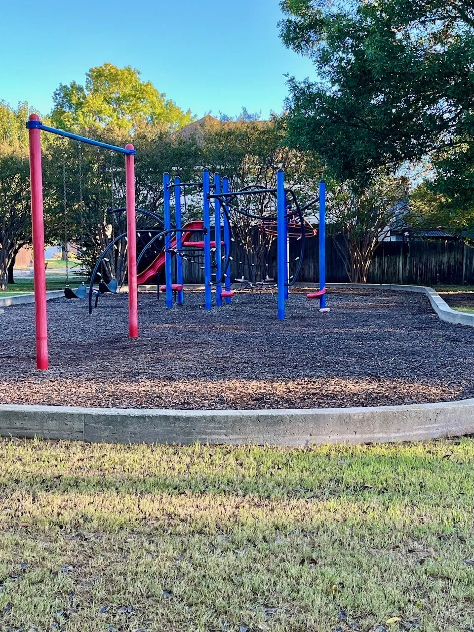 Recreational structure featuring red and blue components, situated on a ground surface of dark material