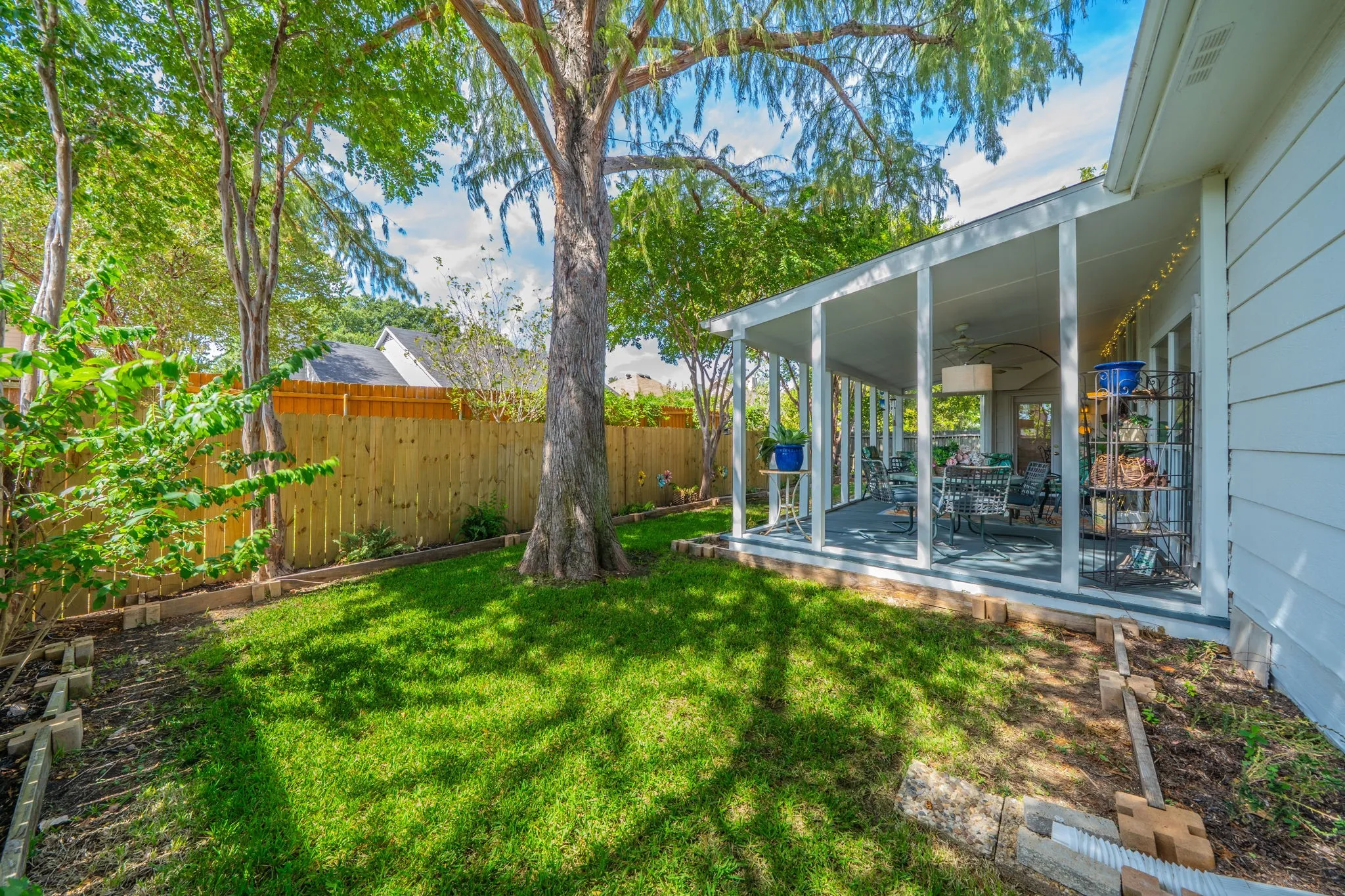 Expansive backyard featuring a manicured lawn, mature trees, and a wooden privacy fence