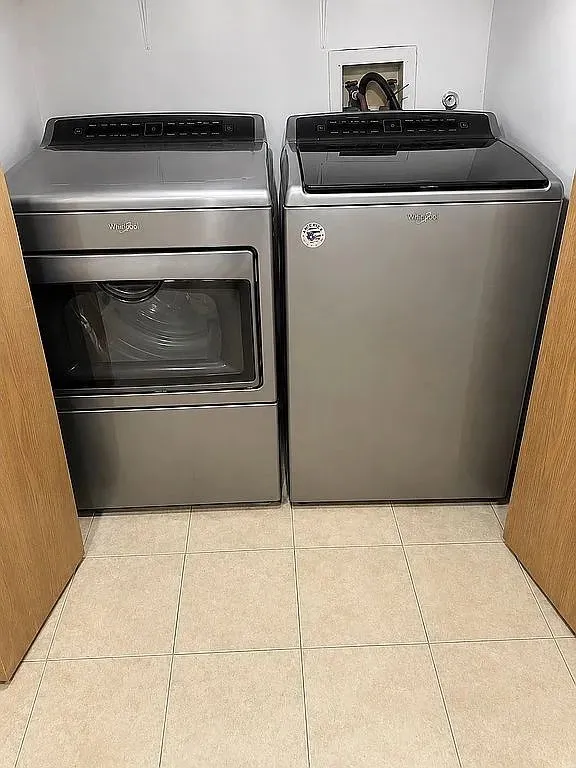 Full-size stainless steel washer and dryer set with a tile floor
