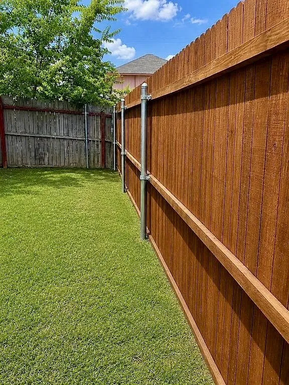Manicured lawn with a privacy fence featuring wood paneling and metal posts