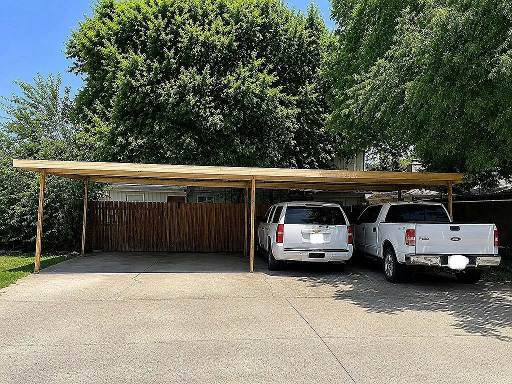 Expansive concrete driveway leading to a multi-vehicle carport structure