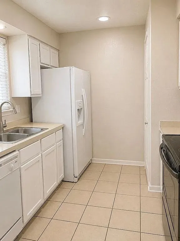 Kitchen featuring white cabinetry, light-toned countertops, ceramic tile flooring, and recessed lighting