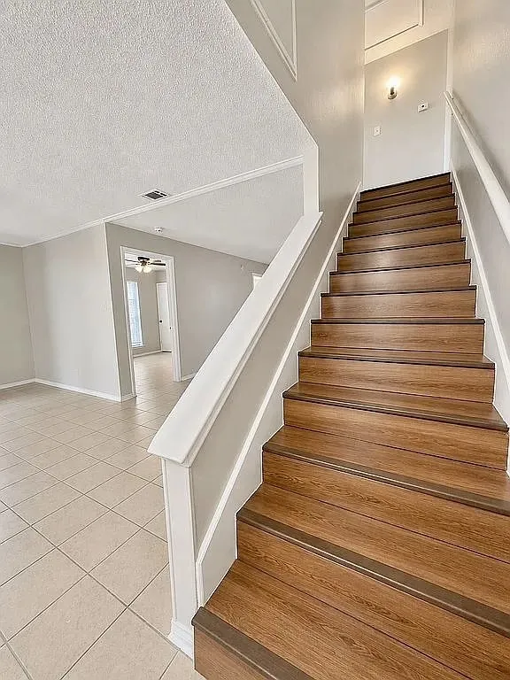 Wood-finish staircase with white handrail and trim