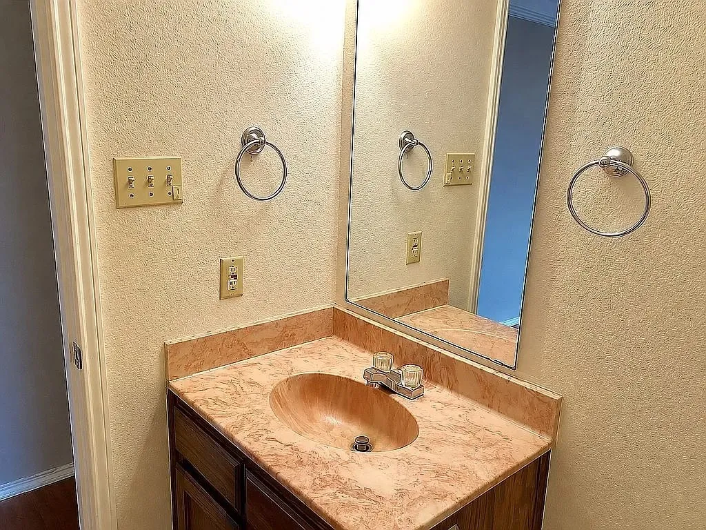 Vanity with a solid surface countertop, integrated sink, and wood-finish cabinetry