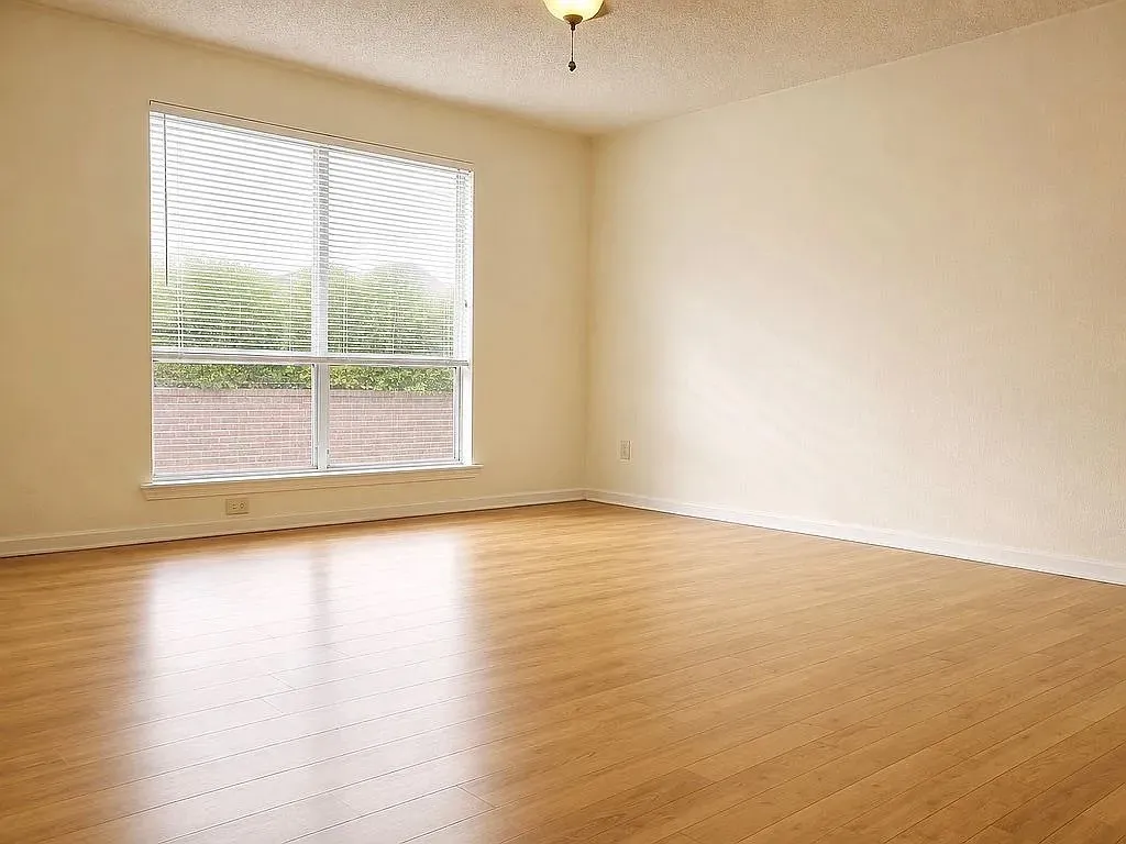 Wood-finish flooring, neutral wall tones, and a large window with horizontal blinds