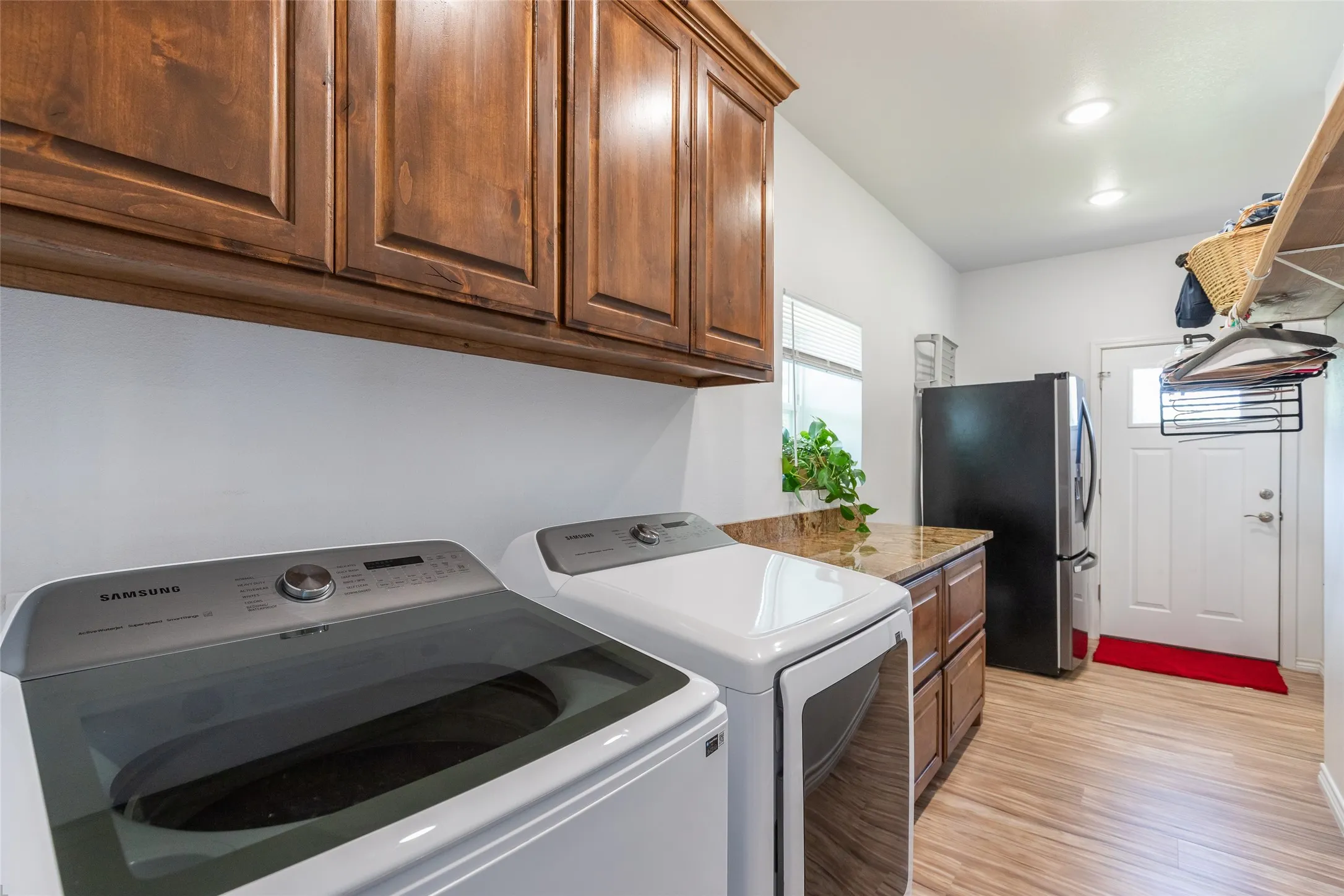 Wood-finish flooring, built-in wooden cabinetry, recessed lighting, window, and a white paneled door