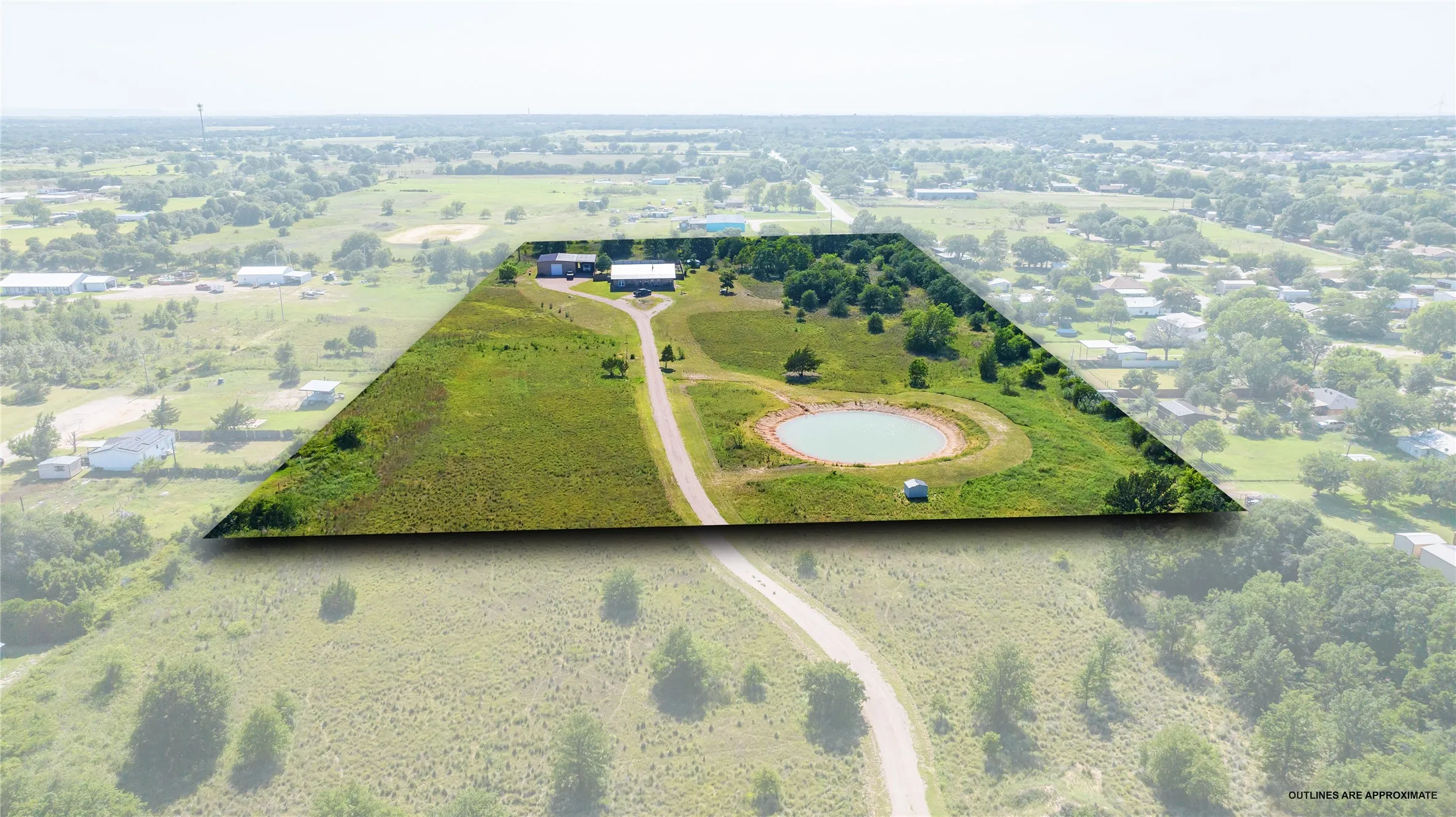 Expansive property featuring a private pond, open grassy areas, mature trees, and a visible structure
