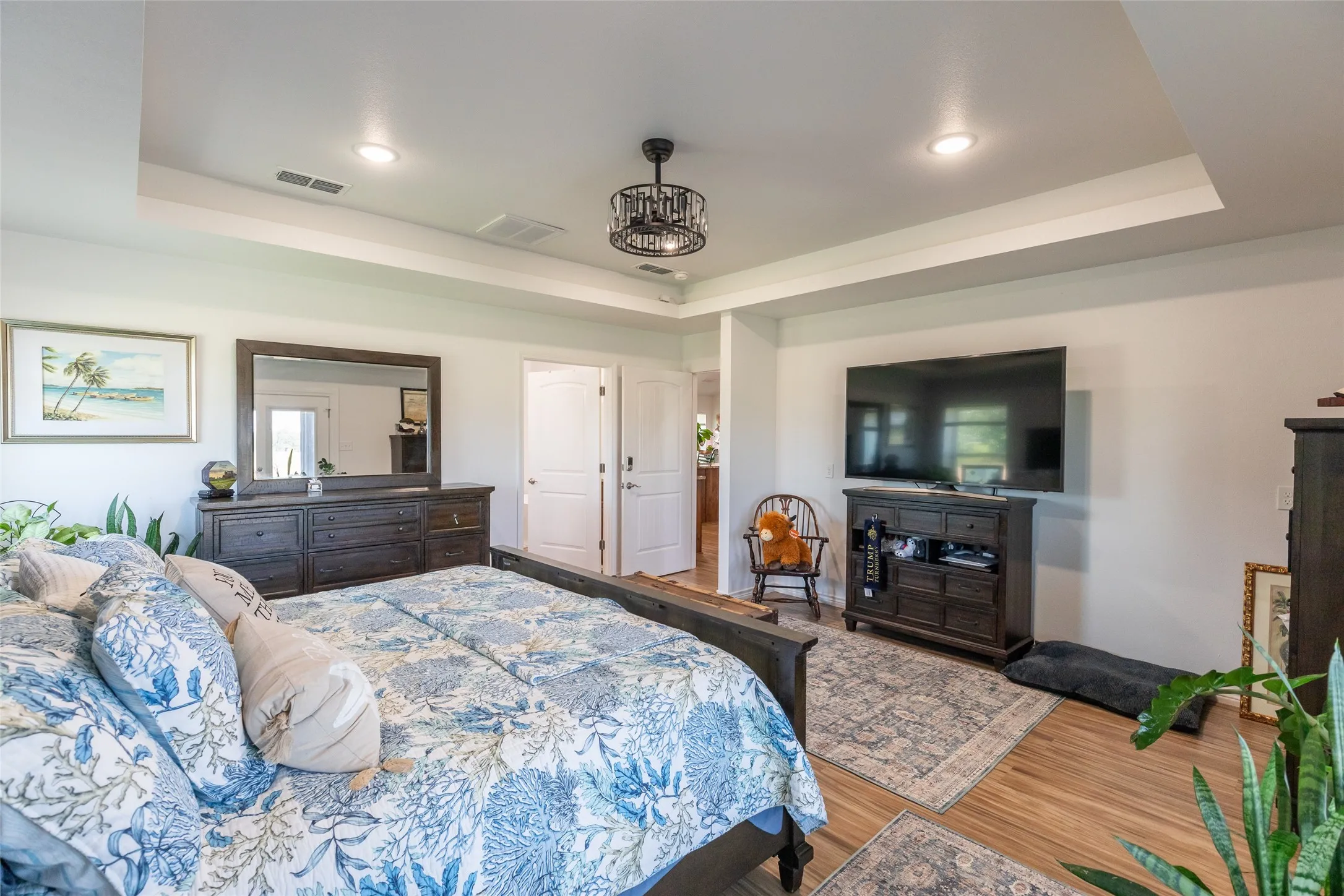 Tray ceiling with recessed lighting, wood-finish flooring, and white interior doors