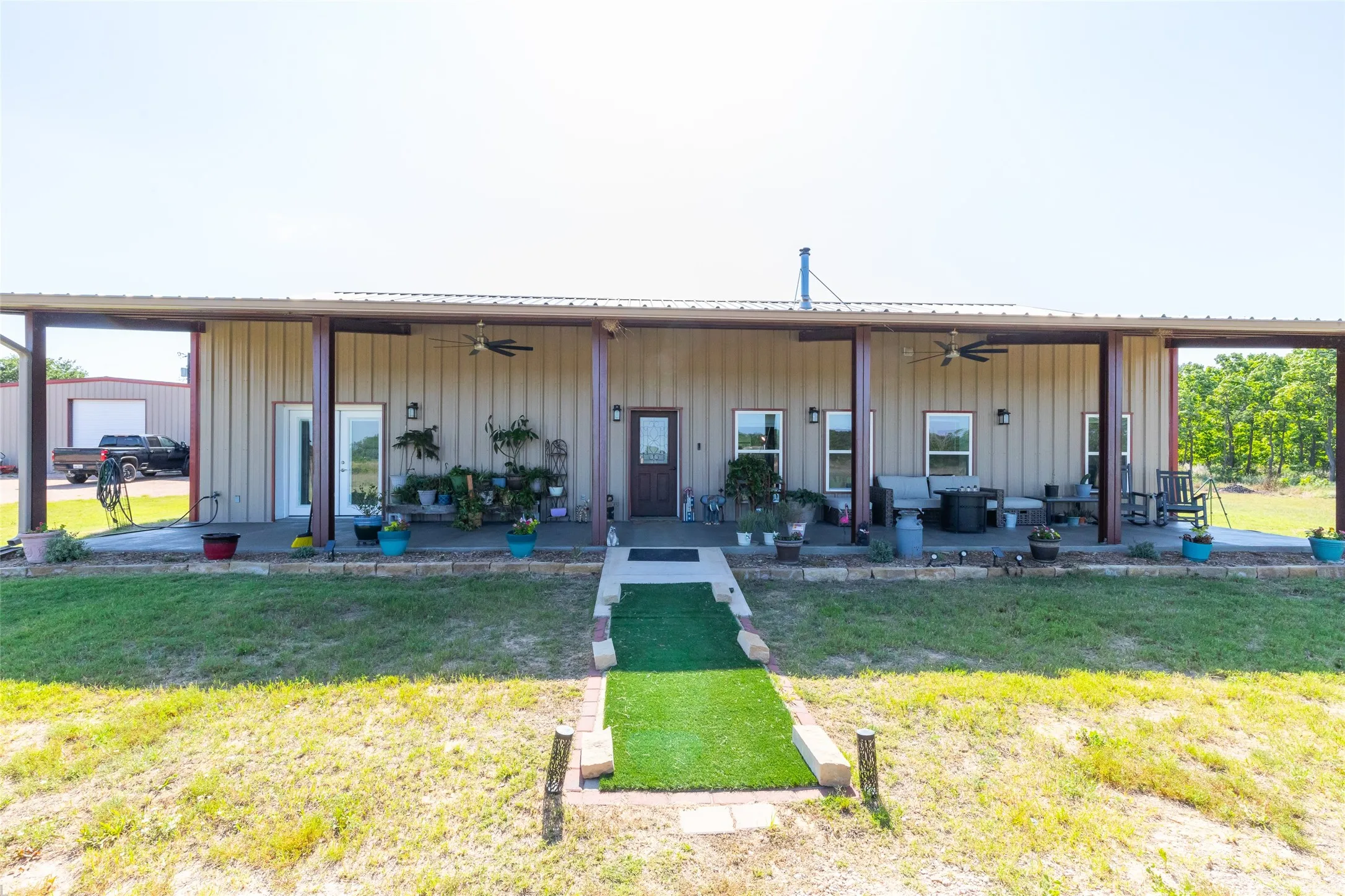Expansive covered porch with multiple ceiling fans, exterior lighting, and a durable metal roof