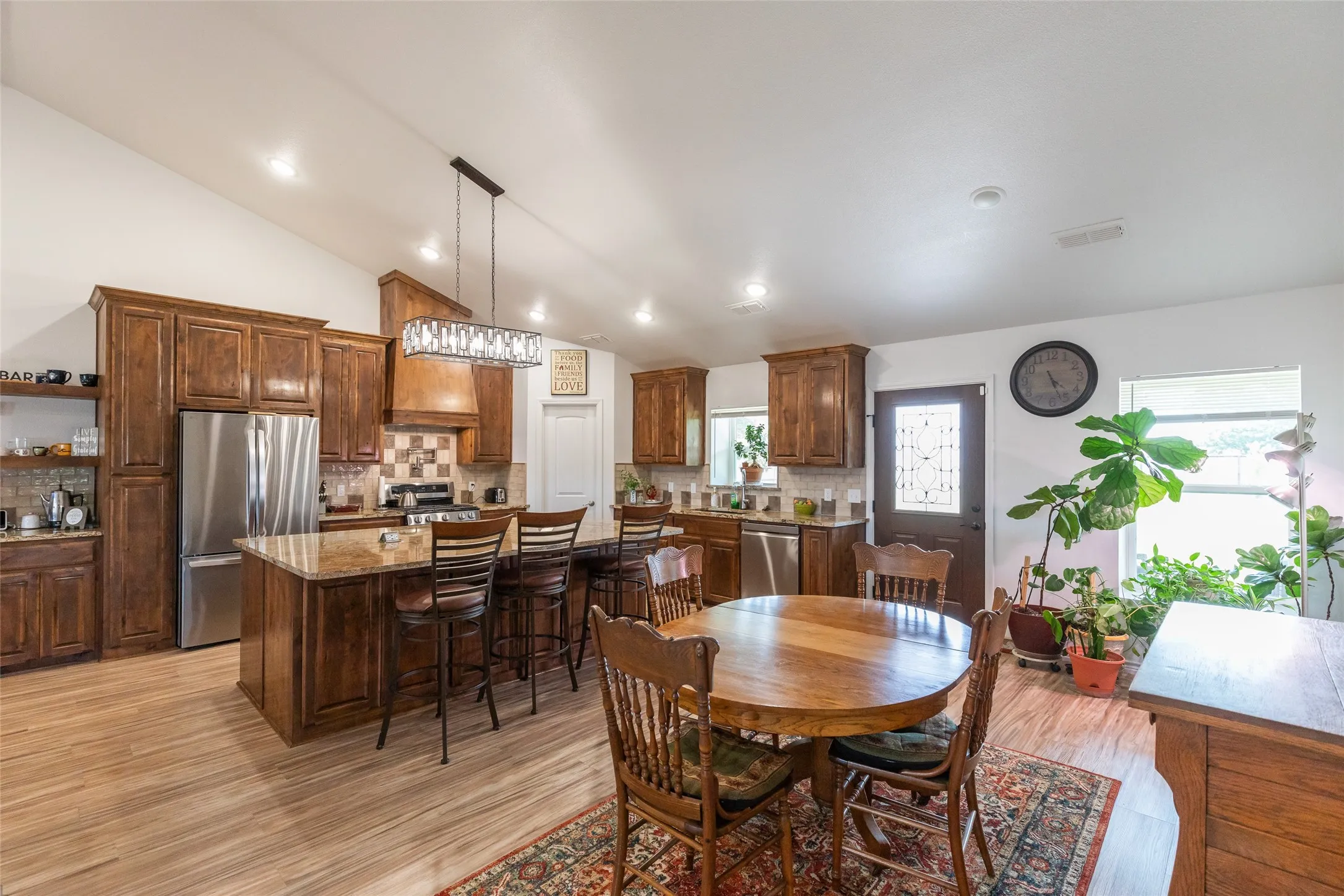 Vaulted ceilings featuring recessed lighting, wood-finish flooring, wood cabinetry, granite countertops, and stainless-steel appliances