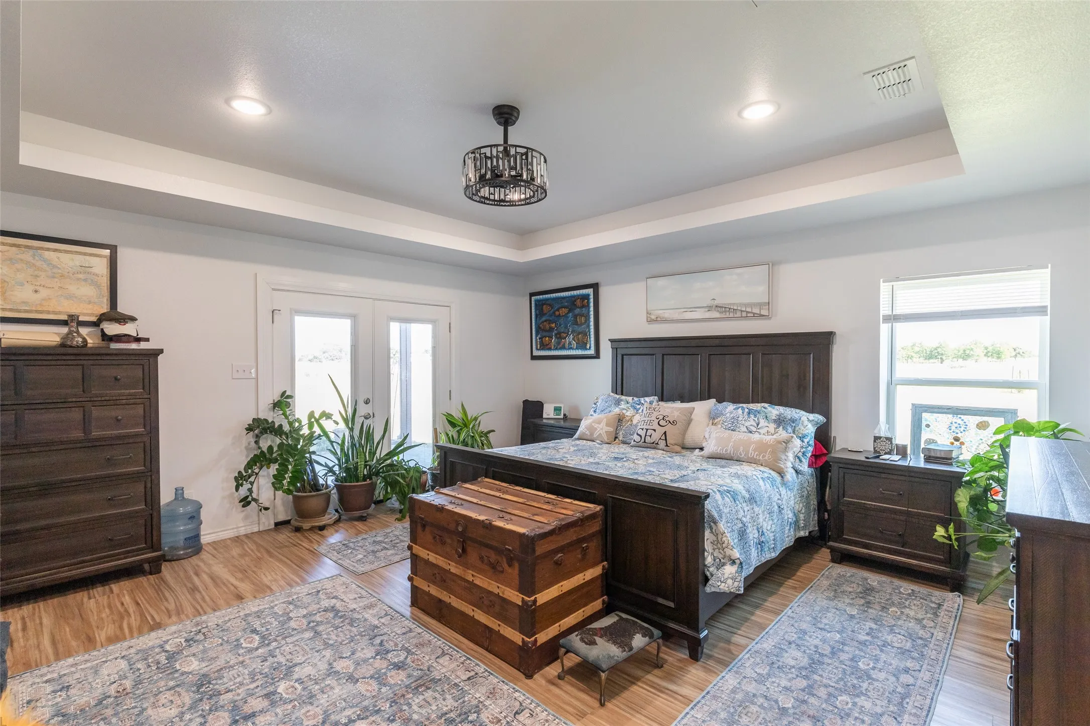 Tray ceiling with recessed lighting, wood-finish flooring, and French doors