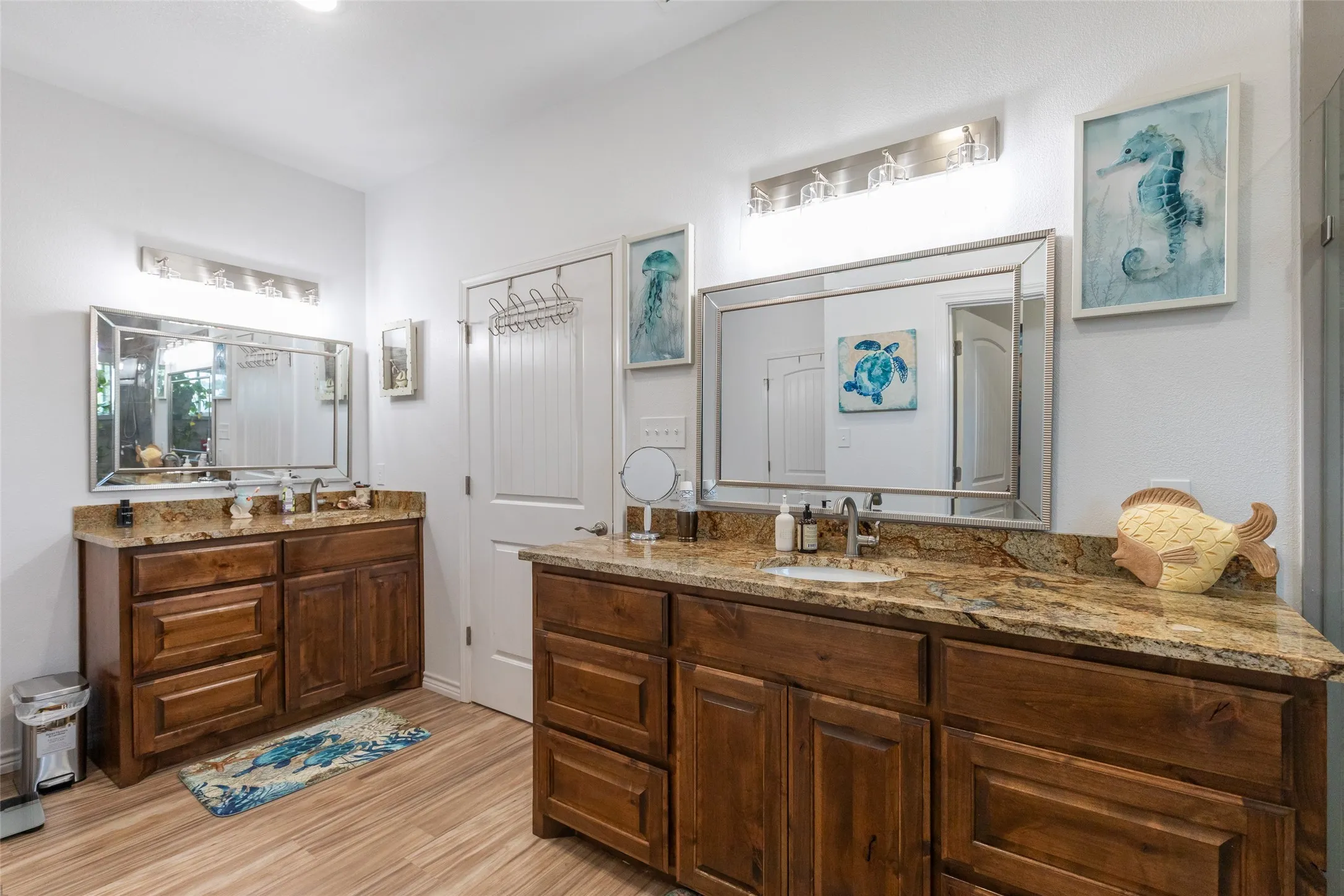 Dual wood-finish vanities with undermount sinks, stone countertops, and framed mirrors
