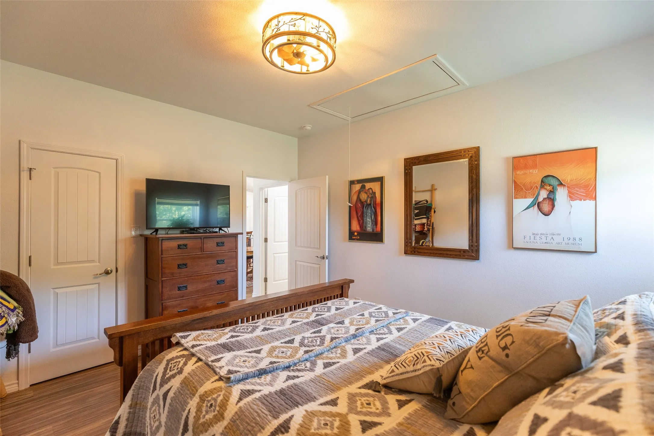 Wood-finish flooring, white paneled doors, and a decorative ceiling light fixture