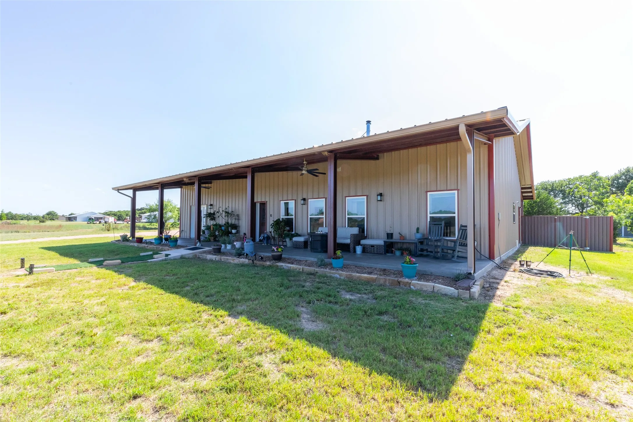 Expansive covered porch with ceiling fans, multiple windows, and metal siding exterior