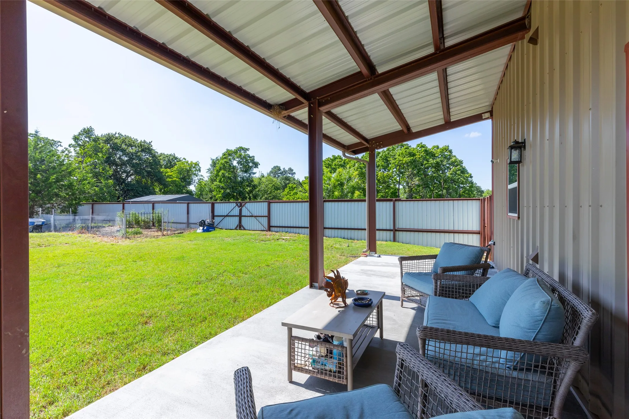 Covered patio with metal roof, durable concrete flooring, and exterior wall lighting