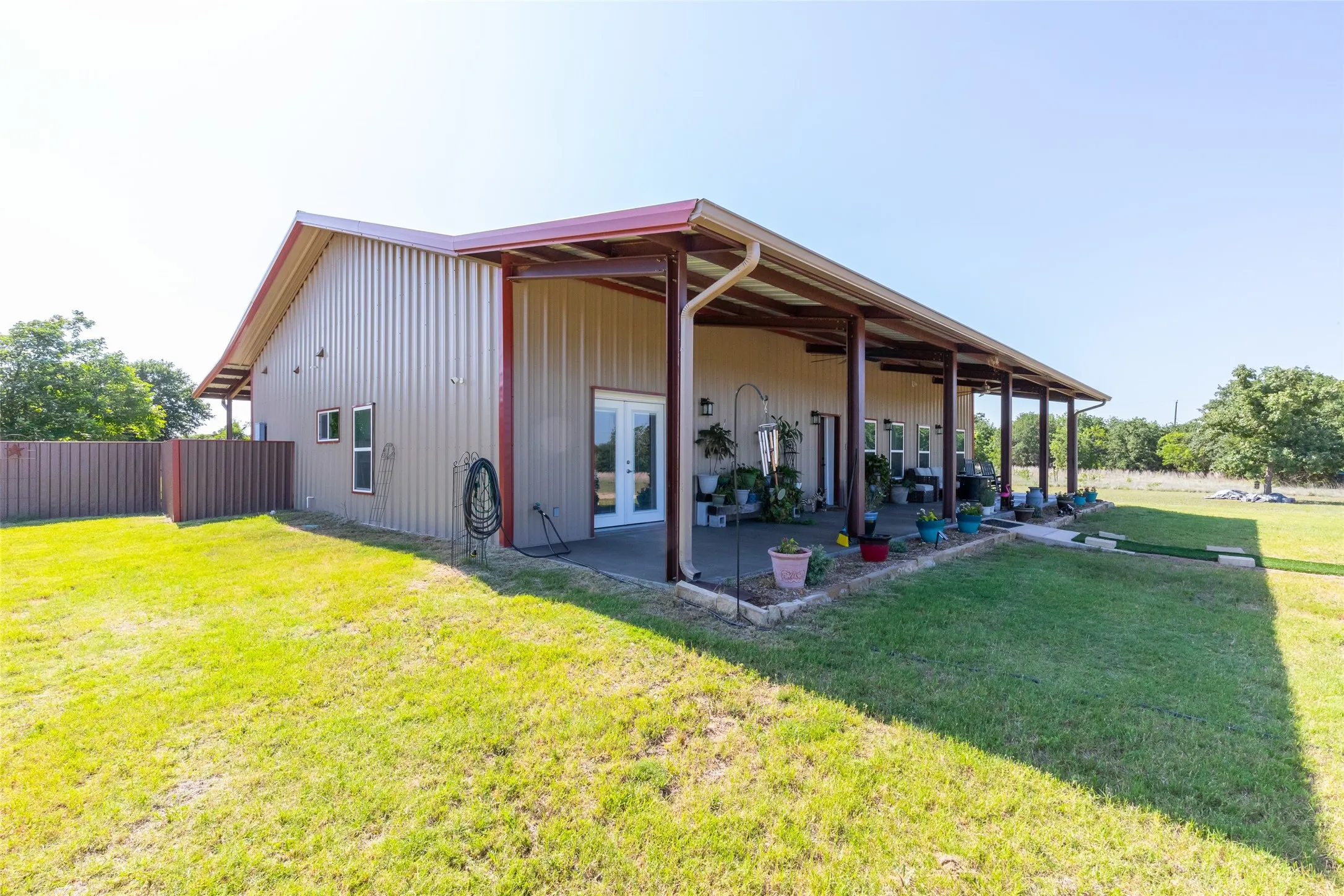 Expansive covered patio extending along the full length of the structure, featuring multiple columns and a durable metal roof