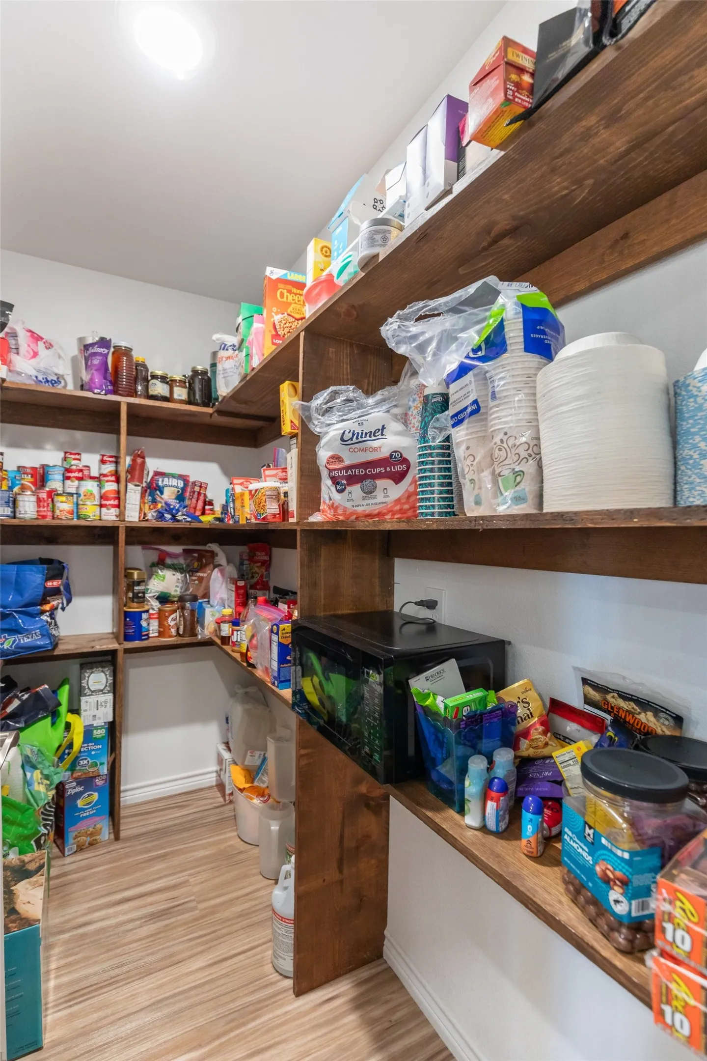 Custom pantry featuring extensive wood-finish shelving and wood-finish flooring