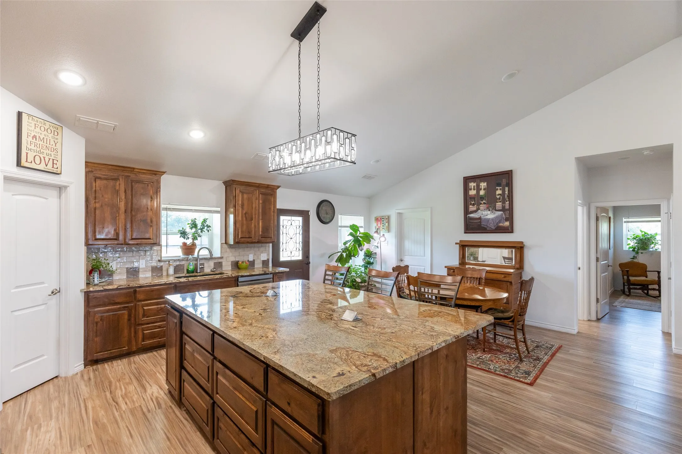 Spacious kitchen featuring a large island with a stone finish countertop, wood-finish cabinetry, and wood-finish flooring