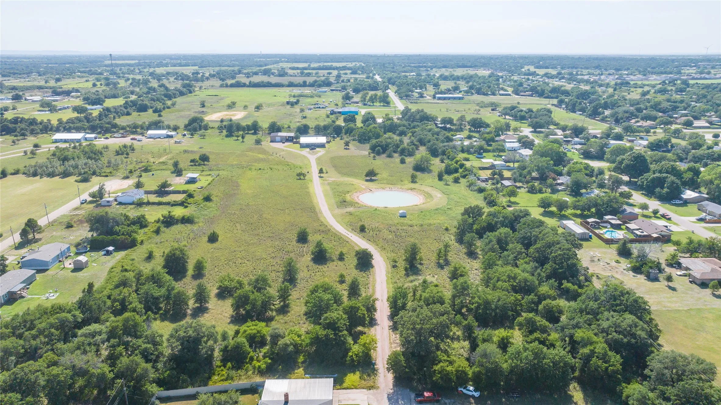 Expansive acreage featuring a private pond, mature trees, and a winding driveway