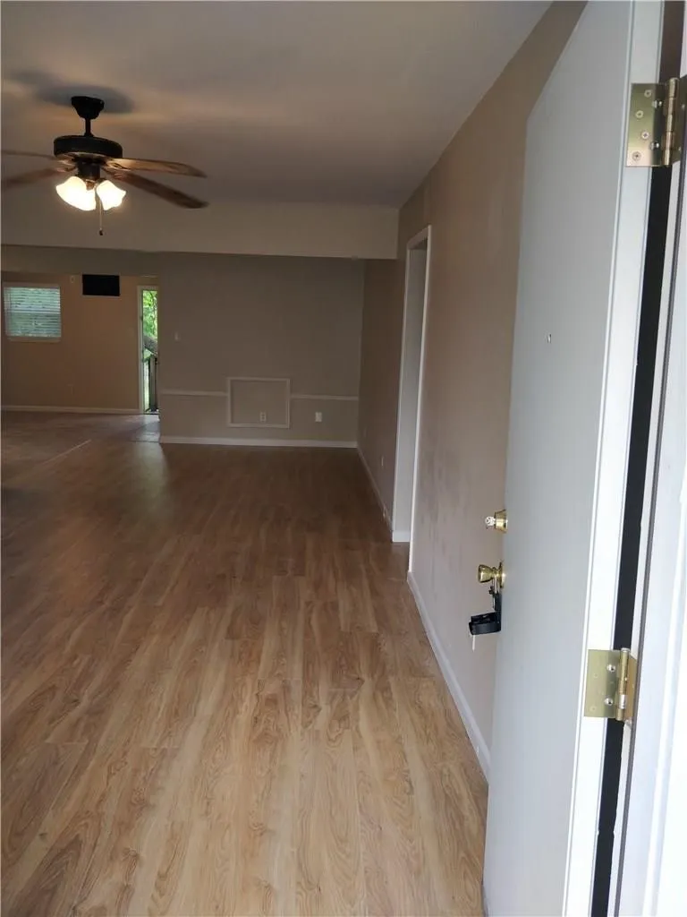 Wood-finish flooring throughout, neutral painted walls, and a ceiling fan with integrated lighting