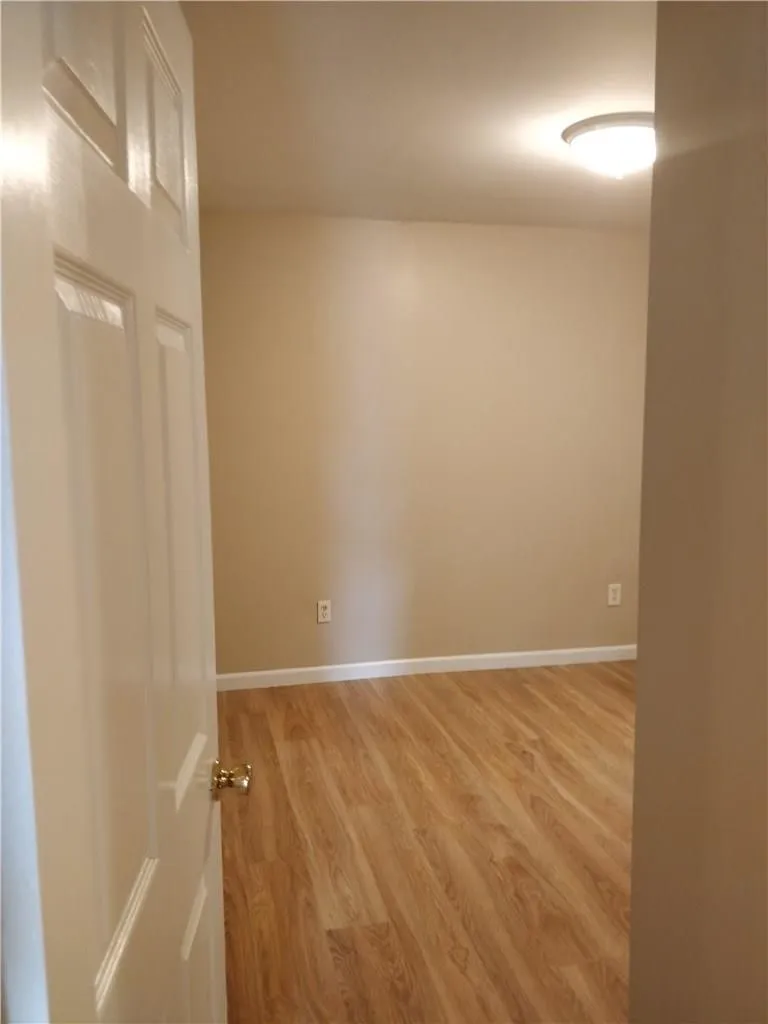 Wood-finish flooring, white trim, neutral wall color, and a flush-mount ceiling light