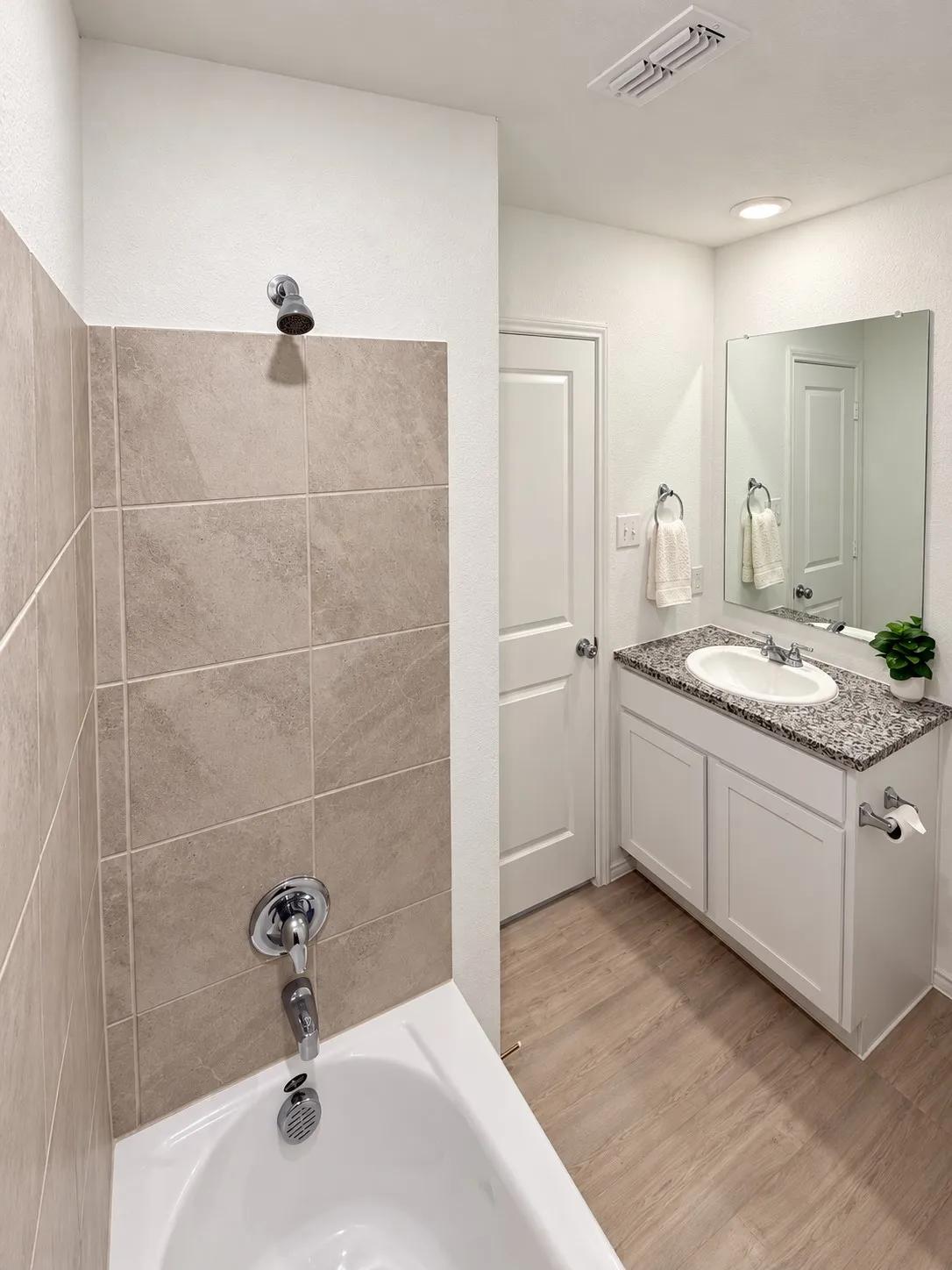 Full bathroom featuring a granite countertop vanity, tub-and-shower combination with tile surround, recessed lighting, and luxury vinyl plank flooring.