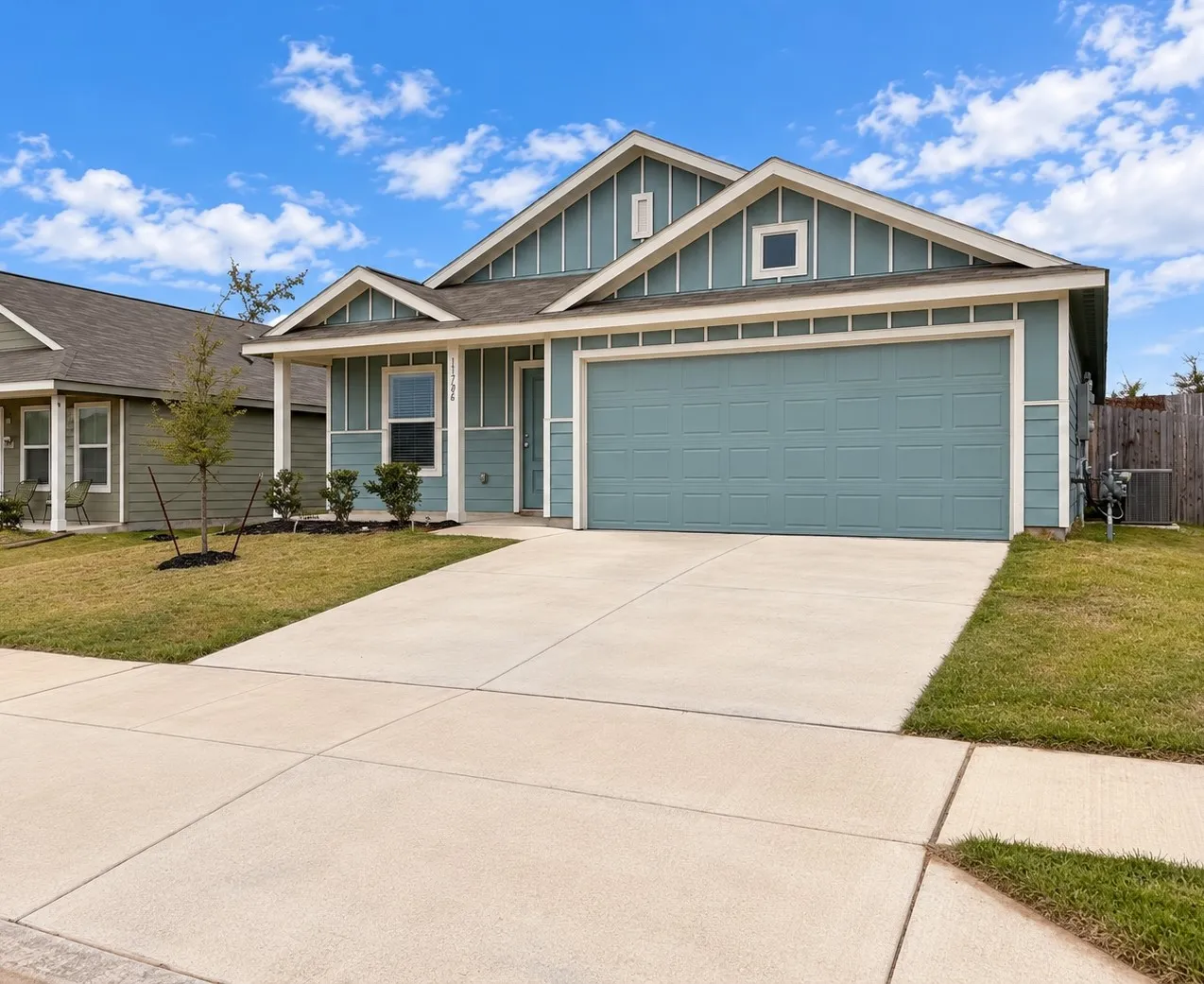 Attractive single-story home featuring blue siding with crisp white trim, an attached two-car garage, covered front entry, and landscaped front yard.