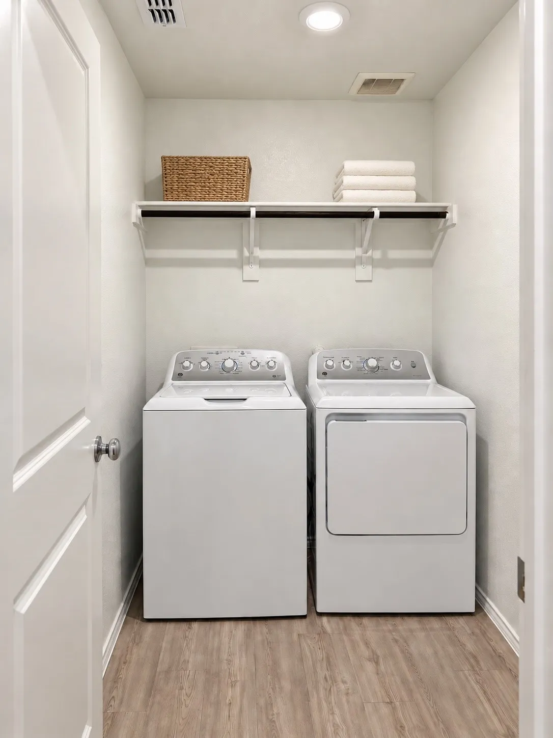 Dedicated laundry area with washer and dryer included, overhead storage shelving, recessed lighting, and luxury vinyl plank flooring.